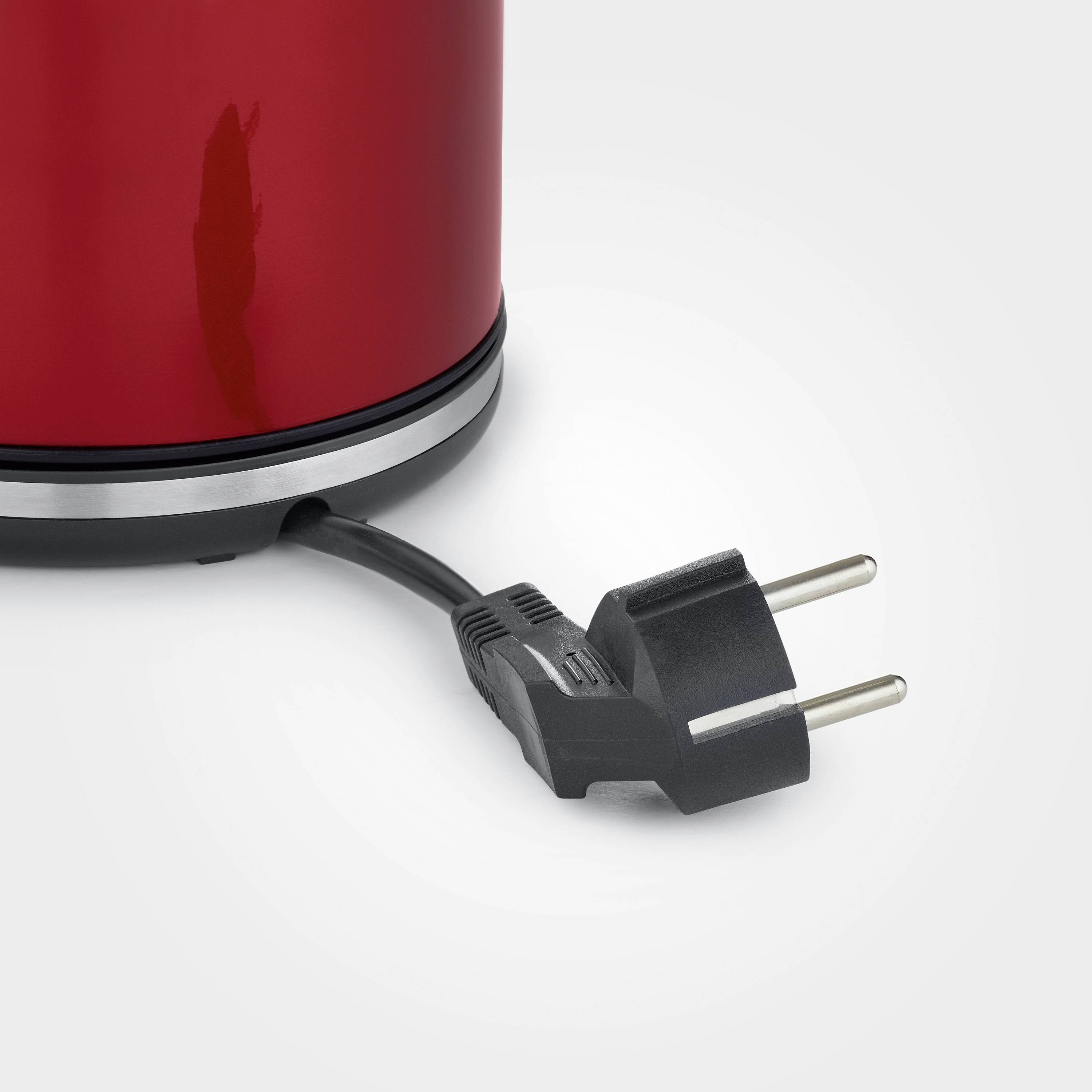 Rode elektrische koffiemachine met uitgetrokken stekker op lichte achtergrond.