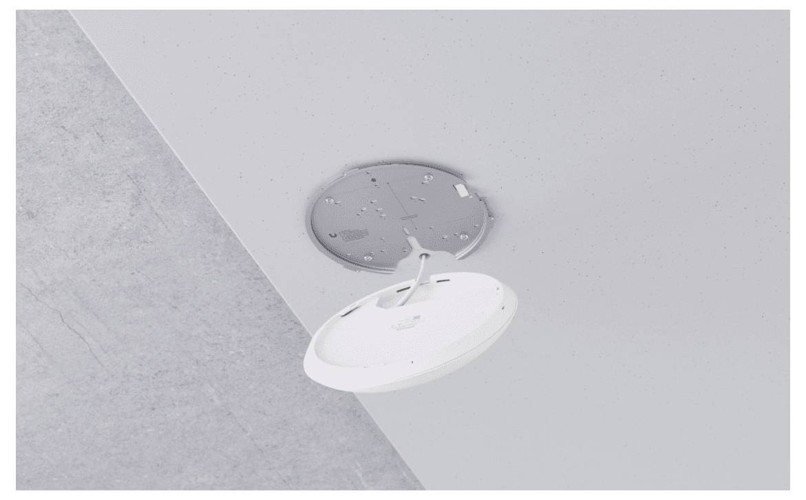 Een beveiligingscamera wordt aan het plafond bevestigd. De camera is rond en gemonteerd in een metalen frame dat aan een betonnen oppervlakte is vastgemaakt.