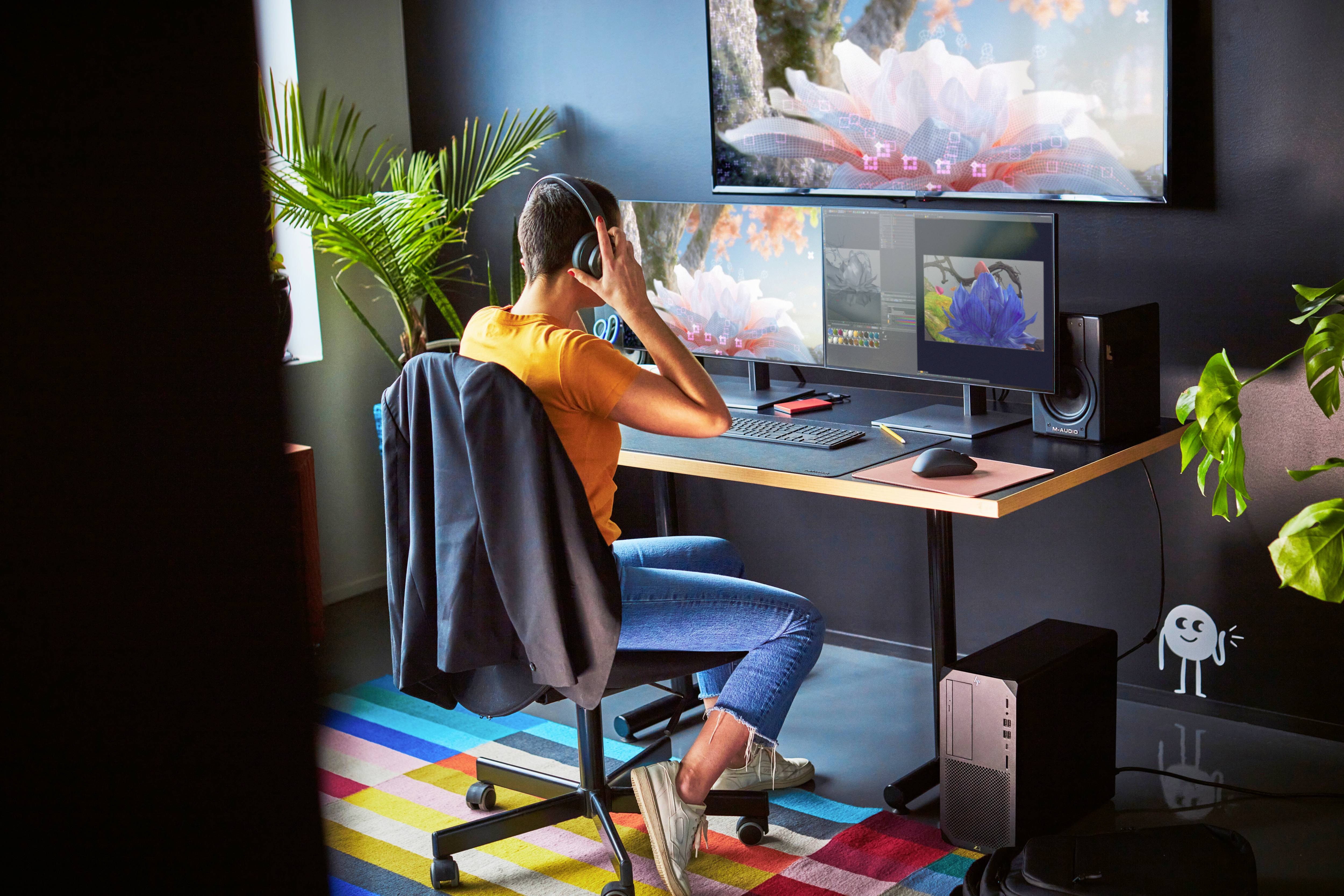 Een persoon zit aan een bureau voor meerdere monitors, draagt koptelefoons en werkt geconcentreerd. De ruimte is modern en licht.