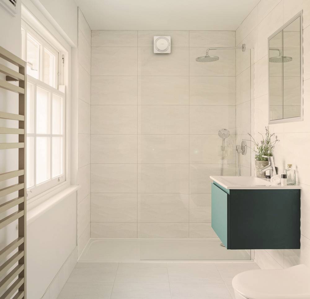 Lichte badkamer met inloopdouche, modern wastafel met groene onderkast en groot raam links.