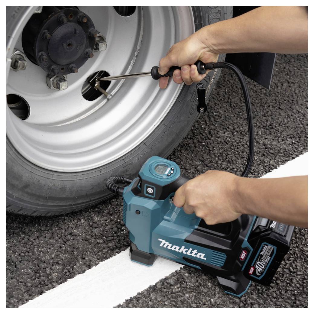 Een persoon vult een autobandenwagen op met behulp van een draagbare Makita-luchtcompressor op een weg. De compressor toont branding met '40V max'.