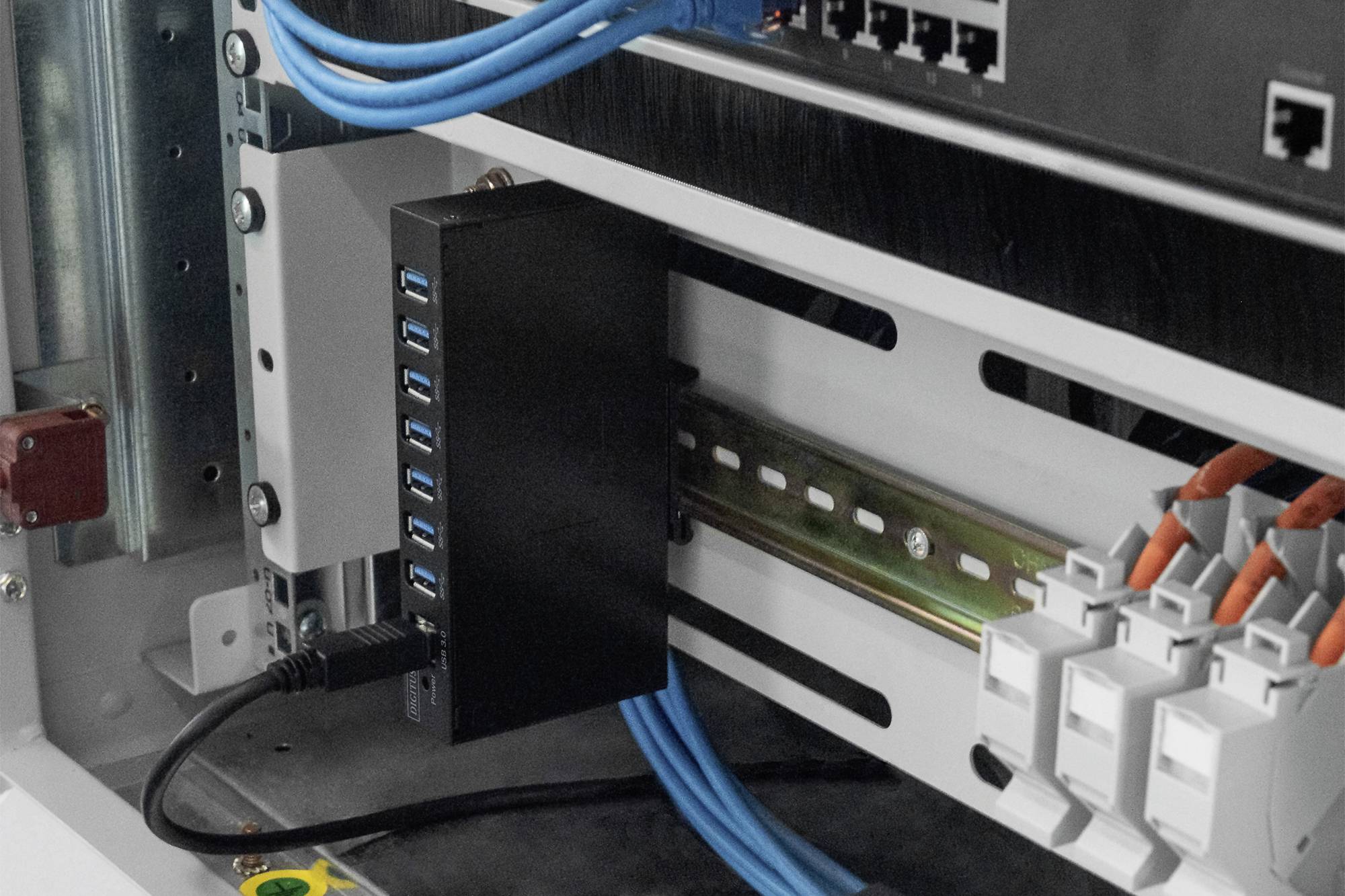 Een schakelkast met blauwe Ethernet-kabels, een USB-hub en zekeringen. Aangesloten techniek voor netwerktoepassingen.