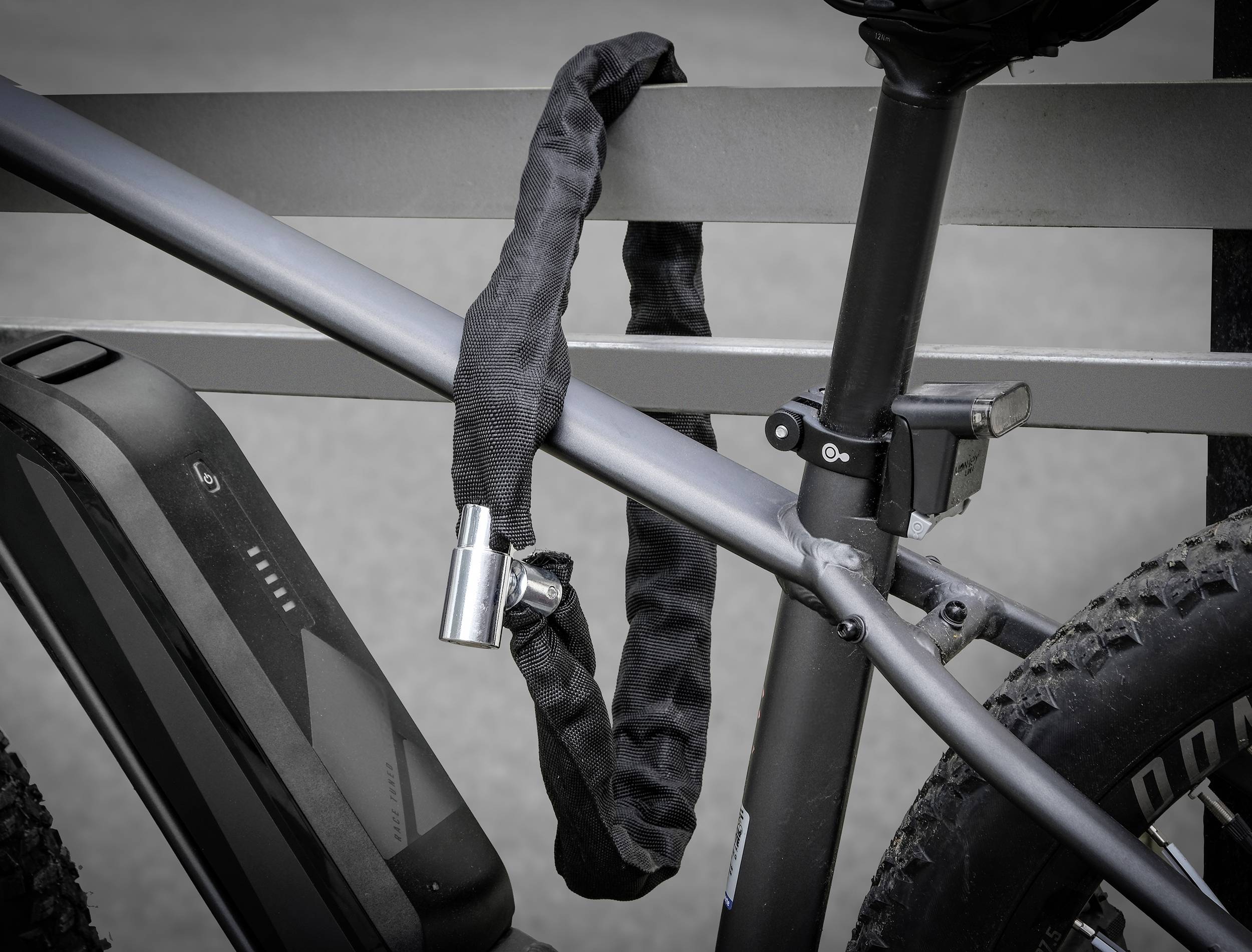 Fietsframe met een slot dat het frame aan een metalen leuning bevestigt. De afbeelding toont een detail van de vergrendeling.