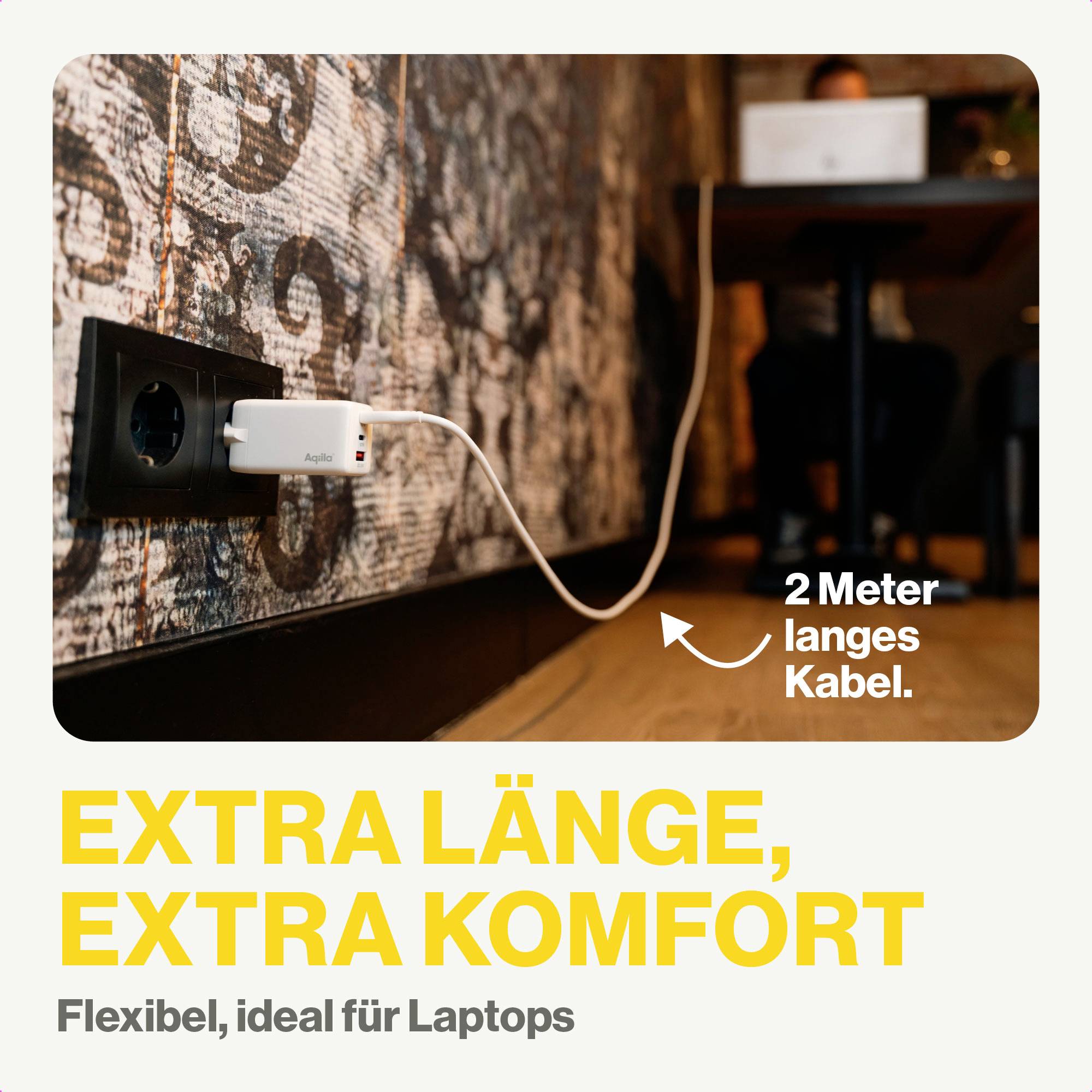 Laadsysteem met 2 meter lang snoer aan wandcontactdoos voor laptops; afbeelding toont persoon die aan een tafel werkt. Tekst: 'EXTRA LENGTE, EXTRA COMFORT. Flexibel, ideaal voor laptops'.