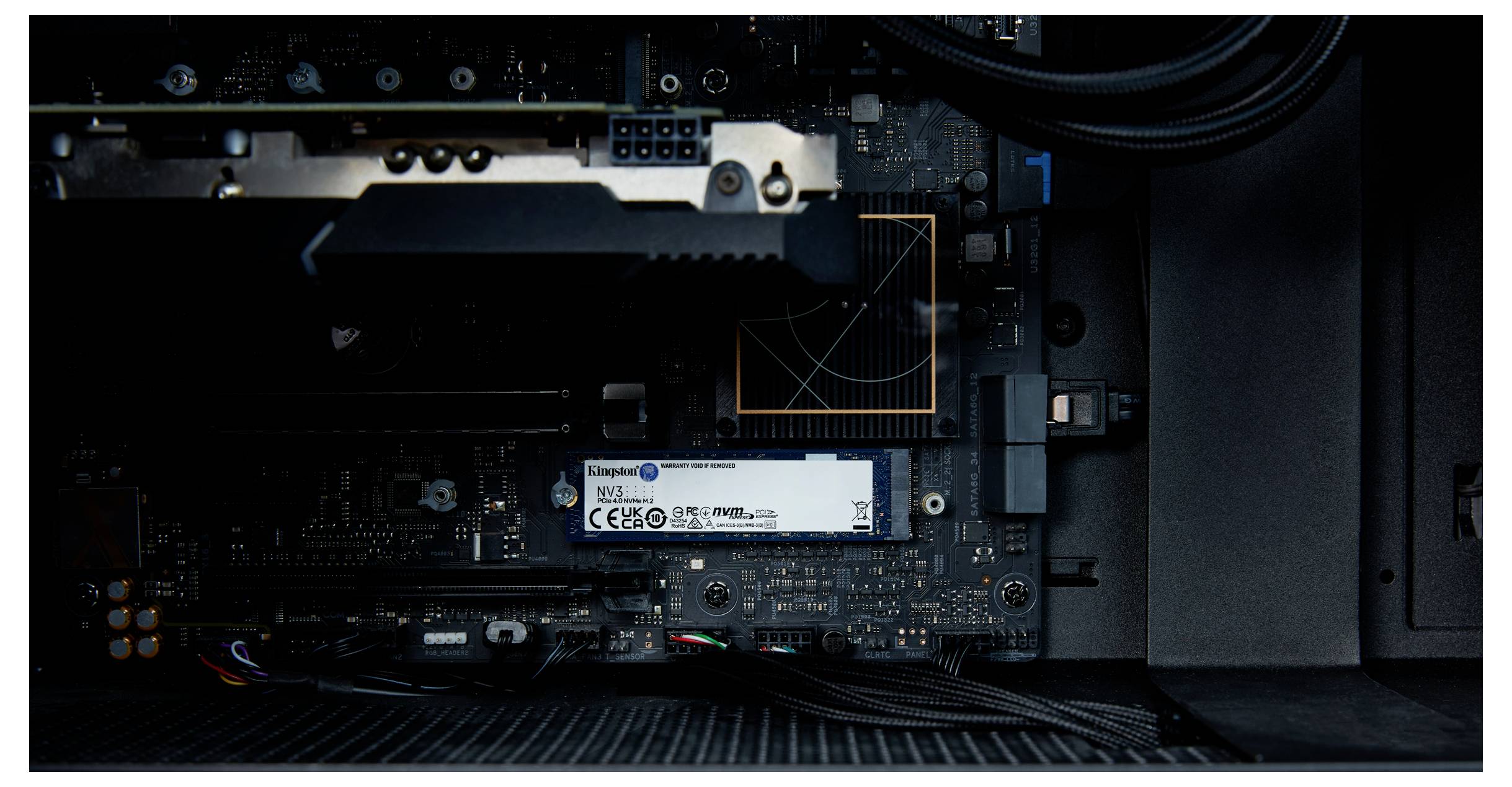 Aanzicht van een geopende computerbehuizing met een vast gemonteerde SSD op het moederbord, omringd door kabels en grafische componenten.