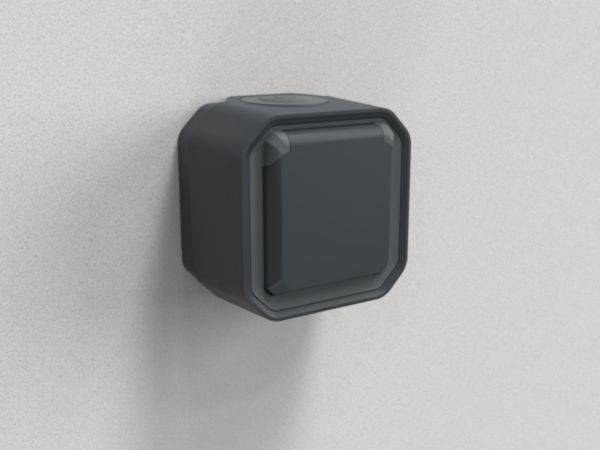 Een zwarte, vierkante schakelaar aan een grijze muur. De schakelaar steekt licht uit en is gemonteerd in een donkere behuizing.