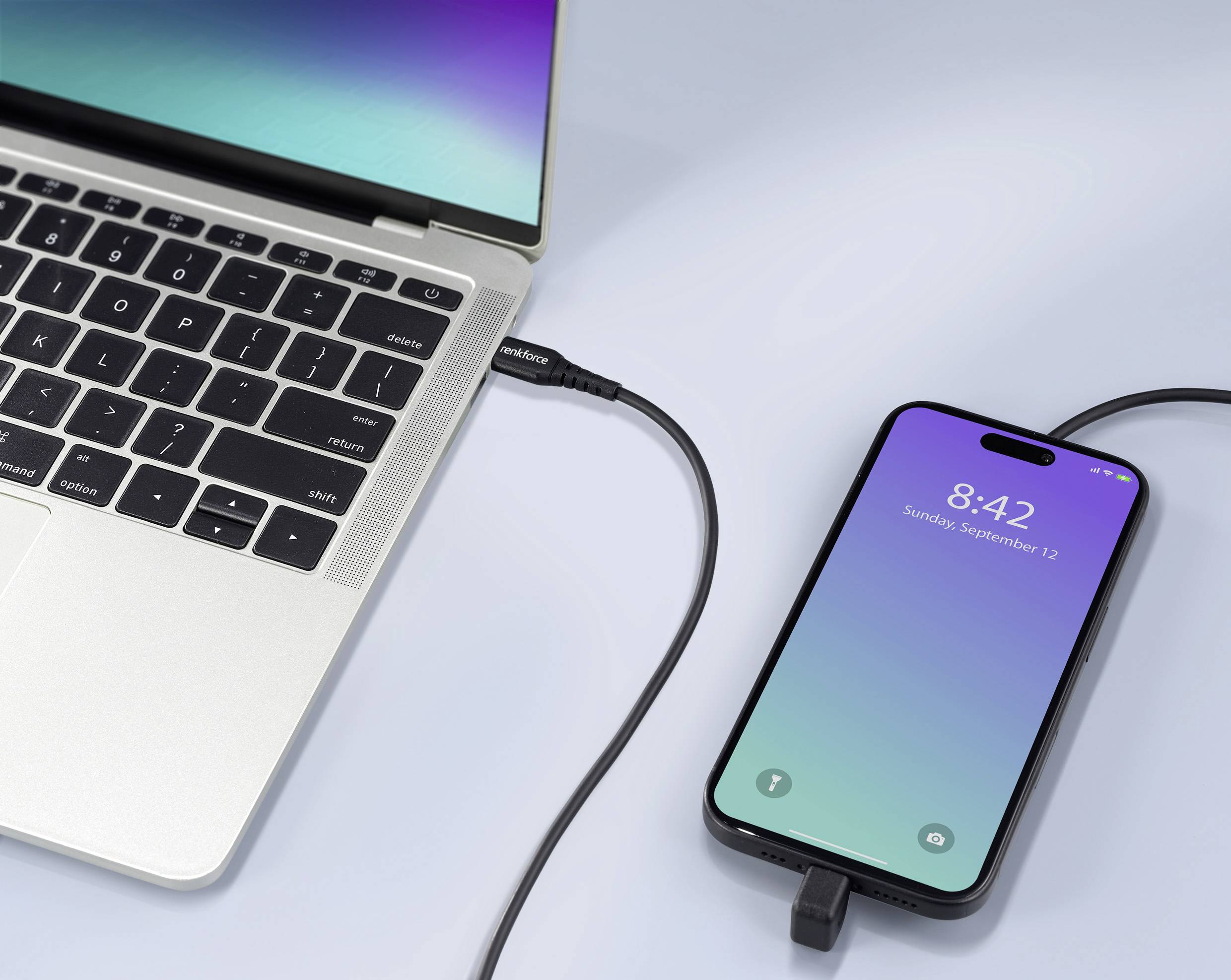 Een laptop is via een kabel verbonden met een smartphone. Het display van de smartphone toont de tijd 8:42 en de datum.