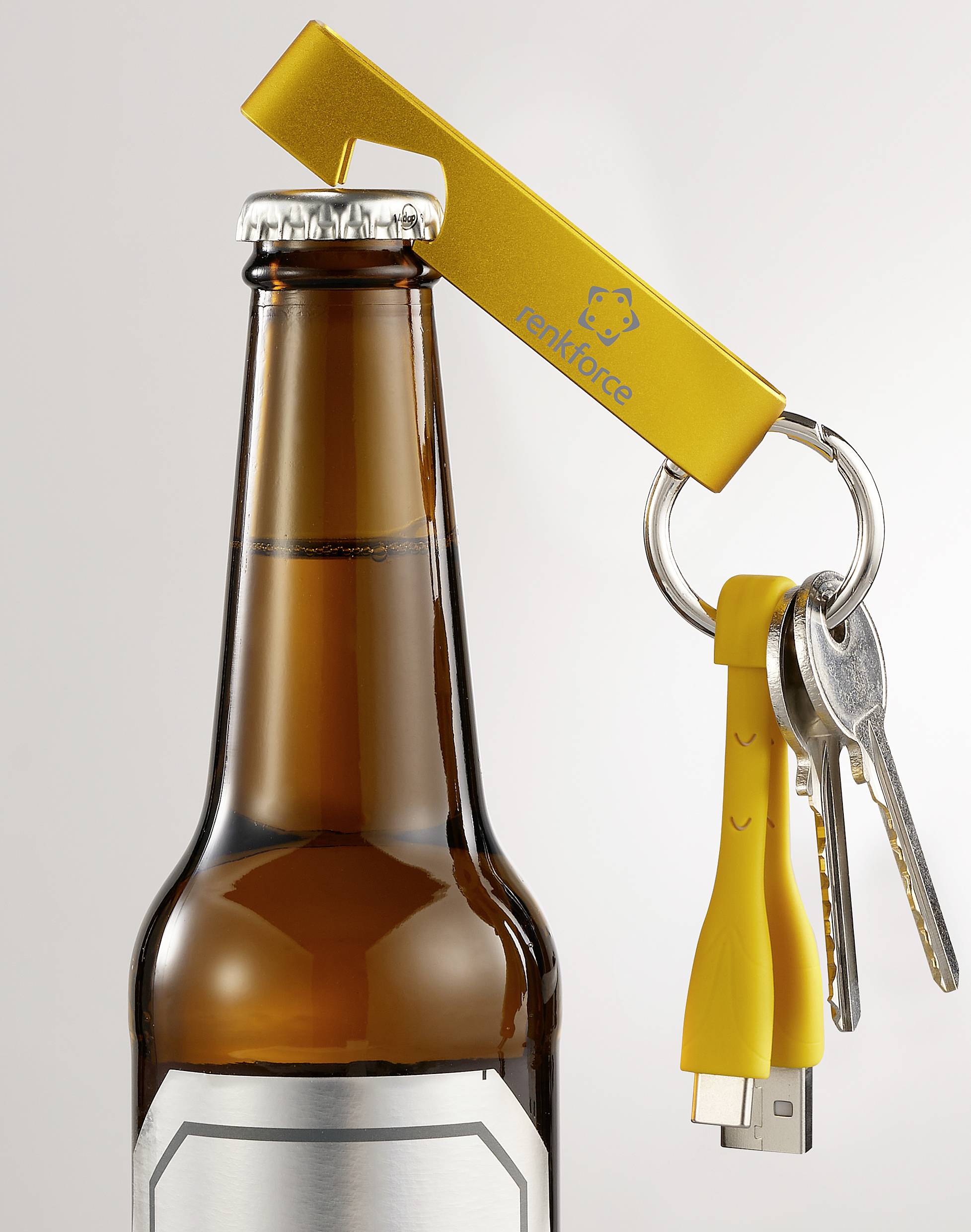 Gele USB-stick-flesopener-combinatie met aangehechte sleutelbos opent een fles. Sleutels en oplaadkabel hangen eraan.