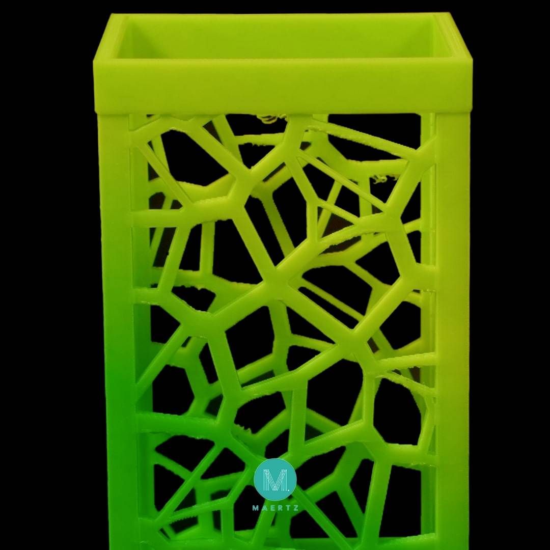 Een rechthoekig, geel-groen plastic voorwerp met een geometrisch, geperforeerd patroon; mogelijkerwijs een decoratieve container.