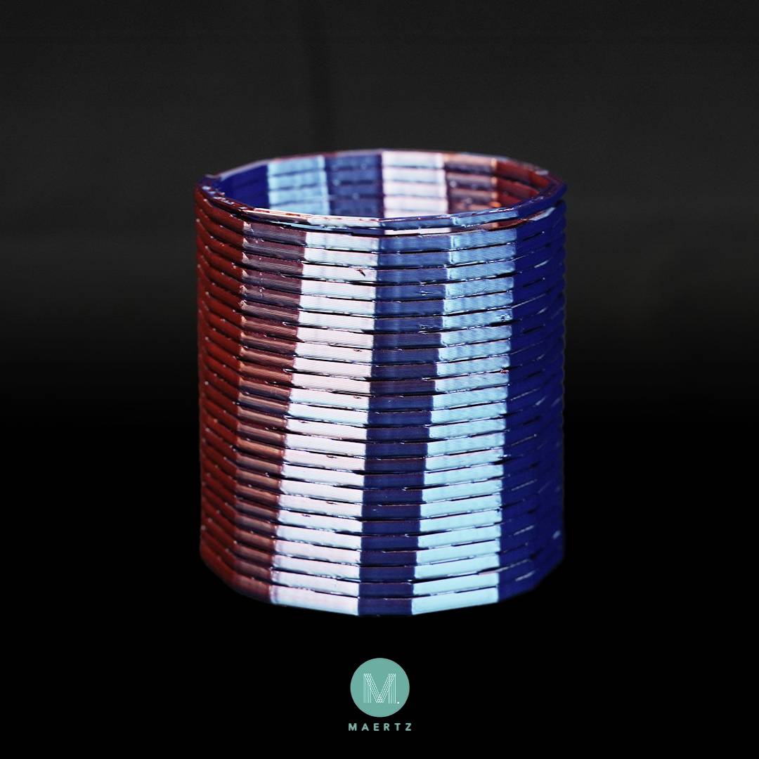 Een cilindrische mand gevlochten uit stroken in rood, wit en blauw.