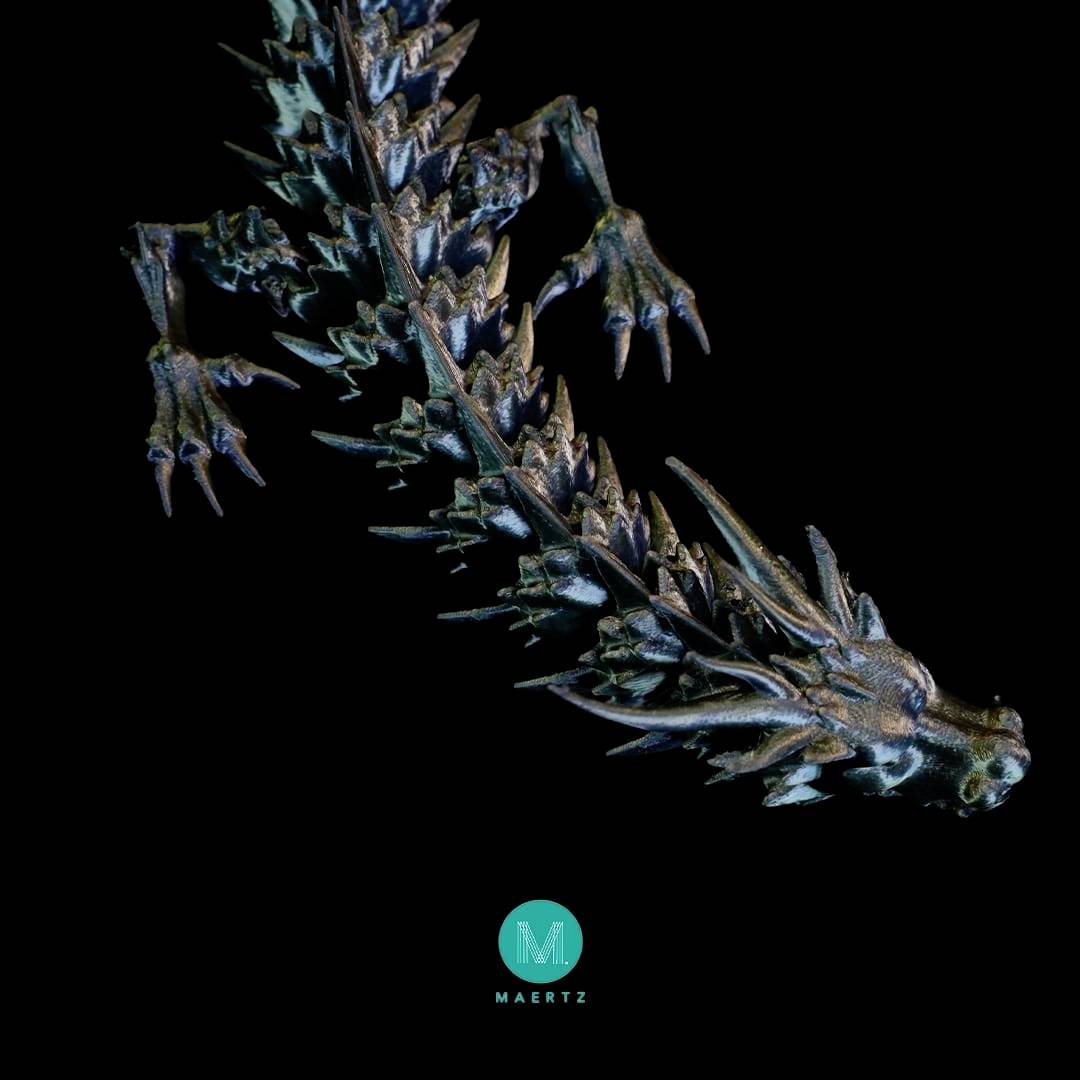 Een bronzen drakenbeeldje met gedetailleerde schubben en klauwen tegen een zwarte achtergrond, onderaan in het midden het logo 'Maertz'.