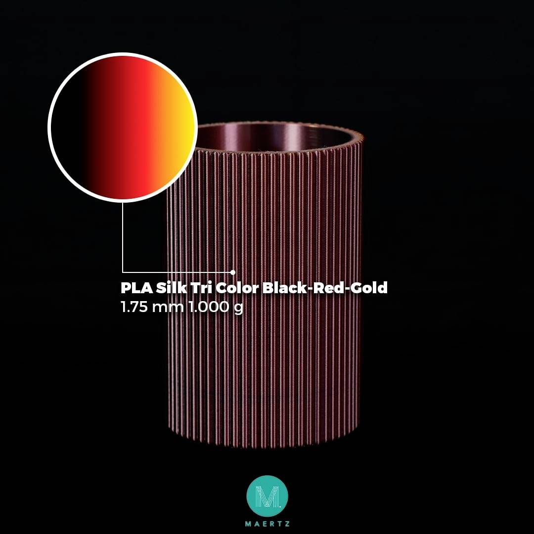 'PLA Zijde Tri Color Zwart-Rood-Goud' filament op een spoel, 1,75 mm dik, 1000 g gewicht. Kleuren lopen van Zwart naar Rood naar Goud.