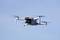 Een witte drone vliegt aan de heldere blauwe lucht, zijn rotorbladen draaien snel.
