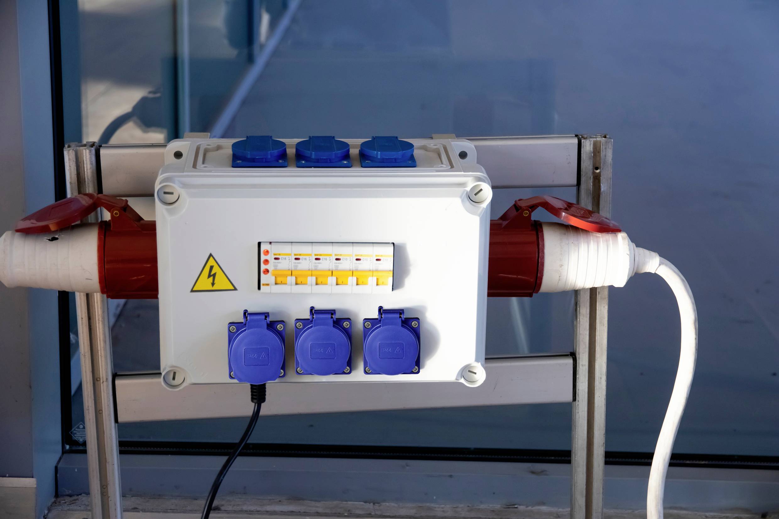 Elektriciteitverdeelkasten met meerdere stopcontacten, schakelaars en beschermende afdekplaten, gemonteerd aan een metalen wand.