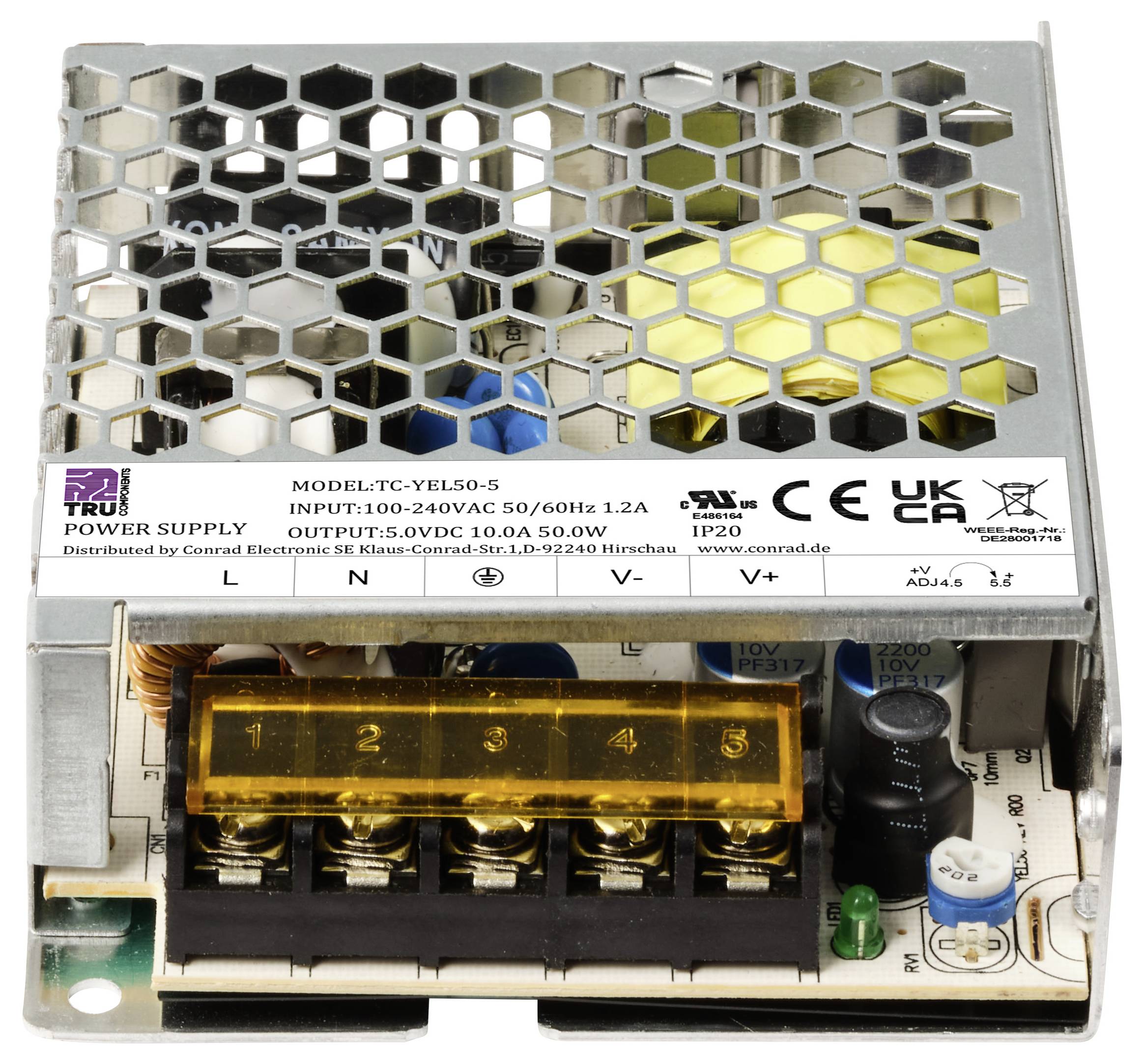 Een open schakelvoeding toont aansluitklemmen, ventilatieroosters en technische specificaties op een etiket.