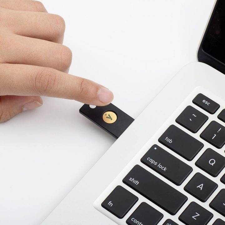 Een hand steekt een USB-stick in een laptop. Op de USB-stick bevindt zich een geel symbool.