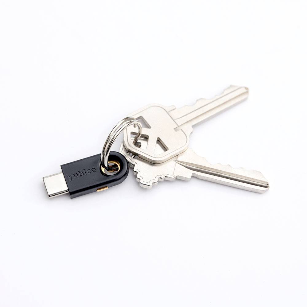 Een USB-C-beveiligingssleutel aan een sleutelhanger met twee huissleutels, weergegeven op een witte achtergrond.