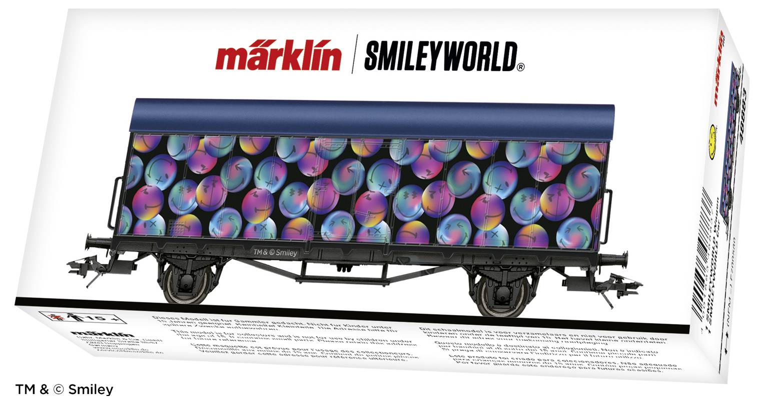 Een Märklin modelspoorwagen-verpakking toont een goederenwagen met een kleurrijk smiley-patroon. Merknaam bovenaan, productdetails onderaan.