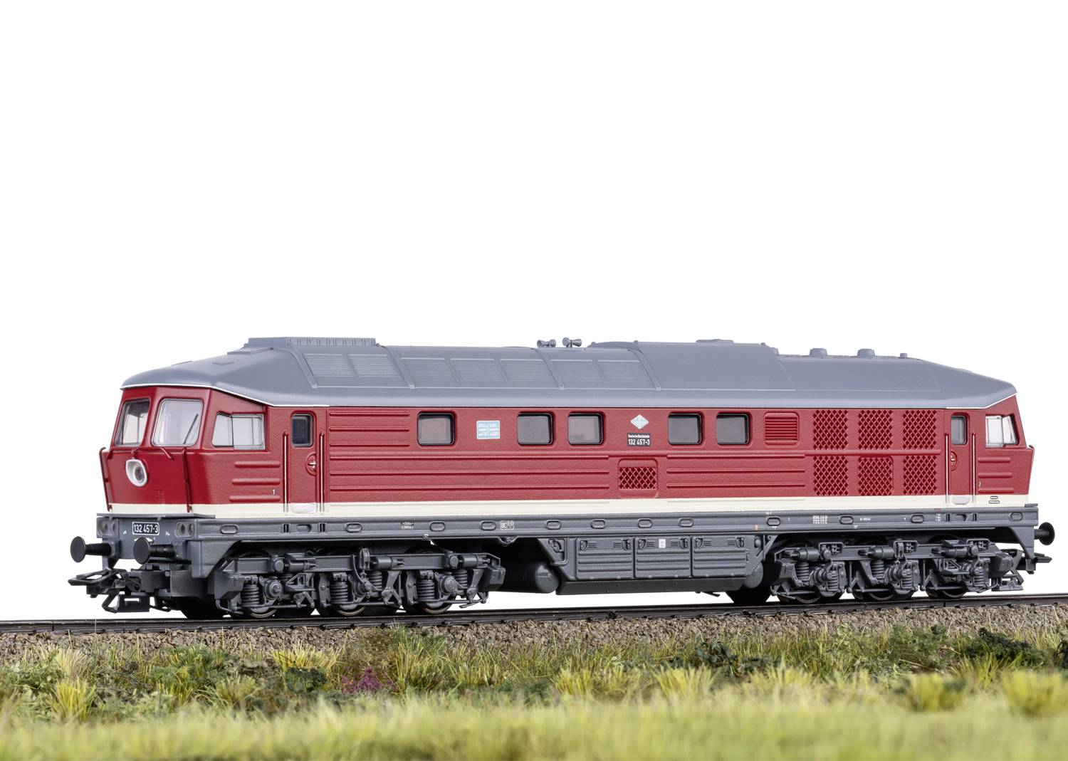 Een rode locomotief rijdt op een spoor door een groene landschap. Hij is gedetailleerd en heeft een modern ontwerp.