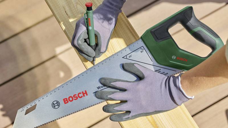 Een persoon tekent met een potlood een markering op hout terwijl hij tegelijkertijd een Bosch-gereedschap als lineaal gebruikt.
