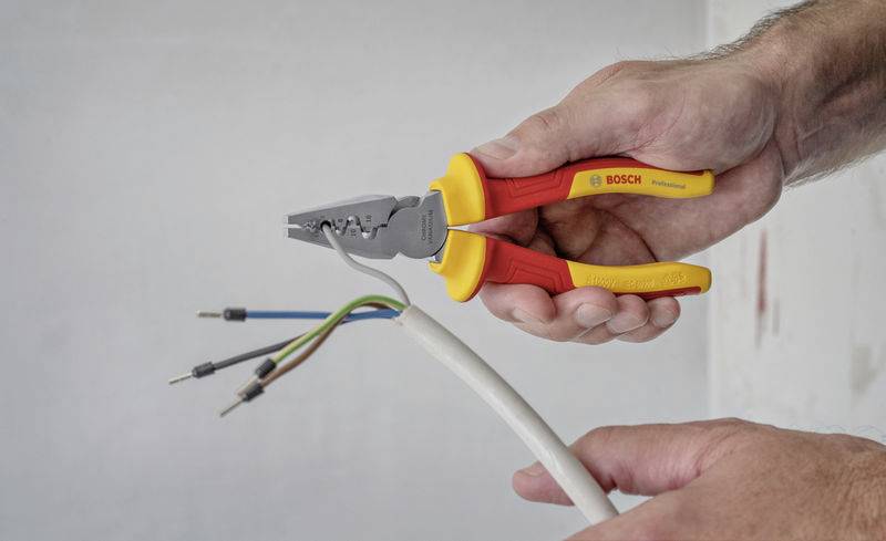 Een persoon houdt een tang en bewerkt een kabel met meerdereaders, omgeven door een heldere, neutrale omgeving.