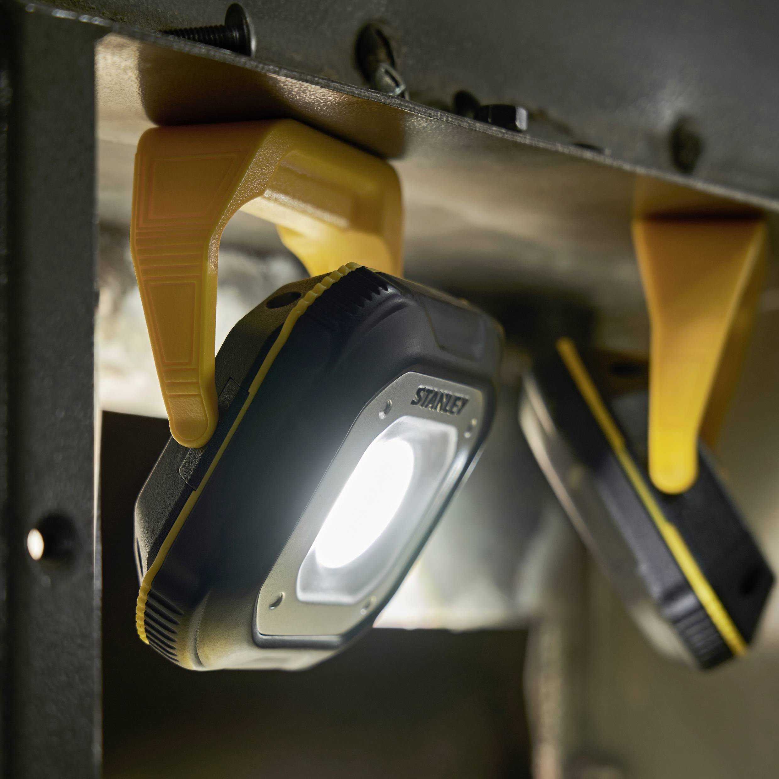 Heldere werkverlichting met clip bevestigd aan een metalen oppervlak, schijnt direct naar beneden. Perfect voor krappe werkruimtes.