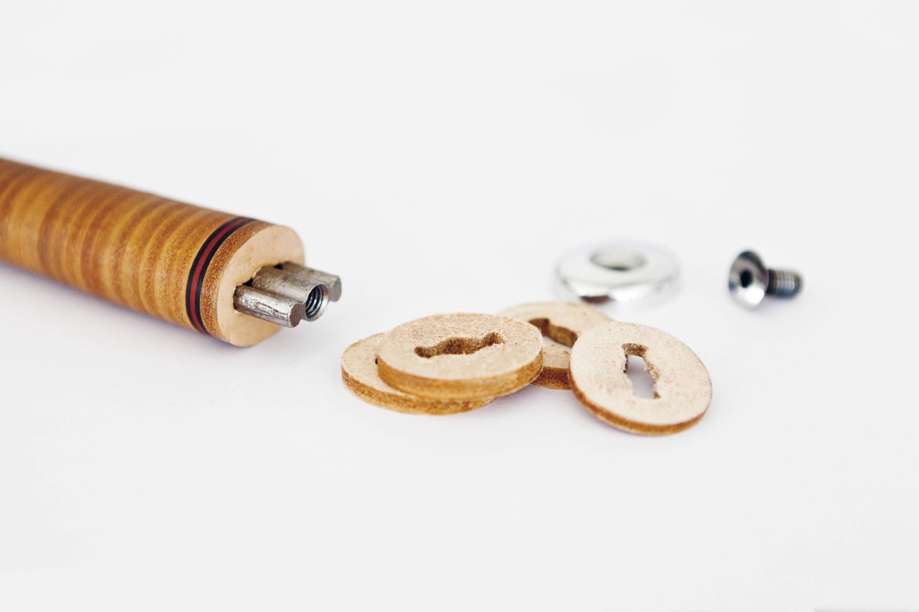 Houten perforator met ronde leren schijven en schroefonderdelen op een witte achtergrond. Gereedschap voor het maken van gaten in leer.