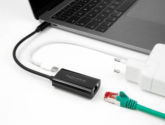 Een laptop is aangesloten op een ethernetadapter. Naast de laptop liggen een netwerkkabel en een oplader.