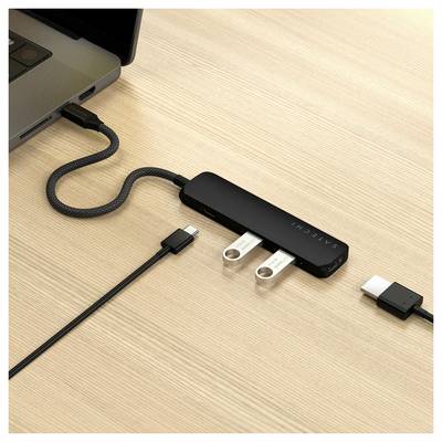 'Een zwarte USB-hub met twee ingestoken USB-sticks is aangesloten op een laptop die op een houten tafel staat.'