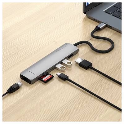 Een USB-C-hub is aangesloten op een laptop. Meerdere kabels en een SD-kaart zijn ingeplugd. Hij maakt het mogelijk om extra apparaten aan te sluiten.