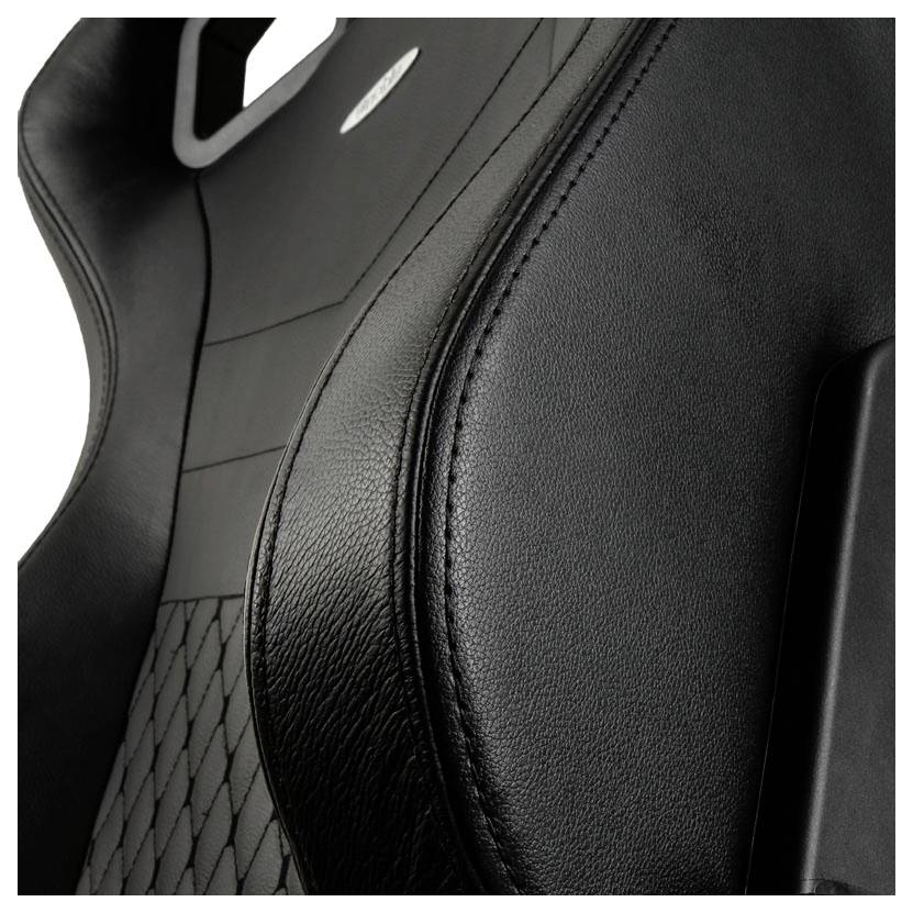 Close-up van een zwarte autostoel in leer met ruitvormige stiknaden en een sportieve ergonomie.