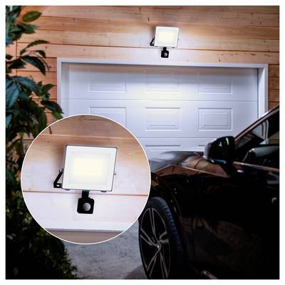 Bewegingsgeactiveerde beveiligingsvloed licht gemonteerd boven een garagedeur, met inzet close-up met het licht aan en de sensorklem ervan.