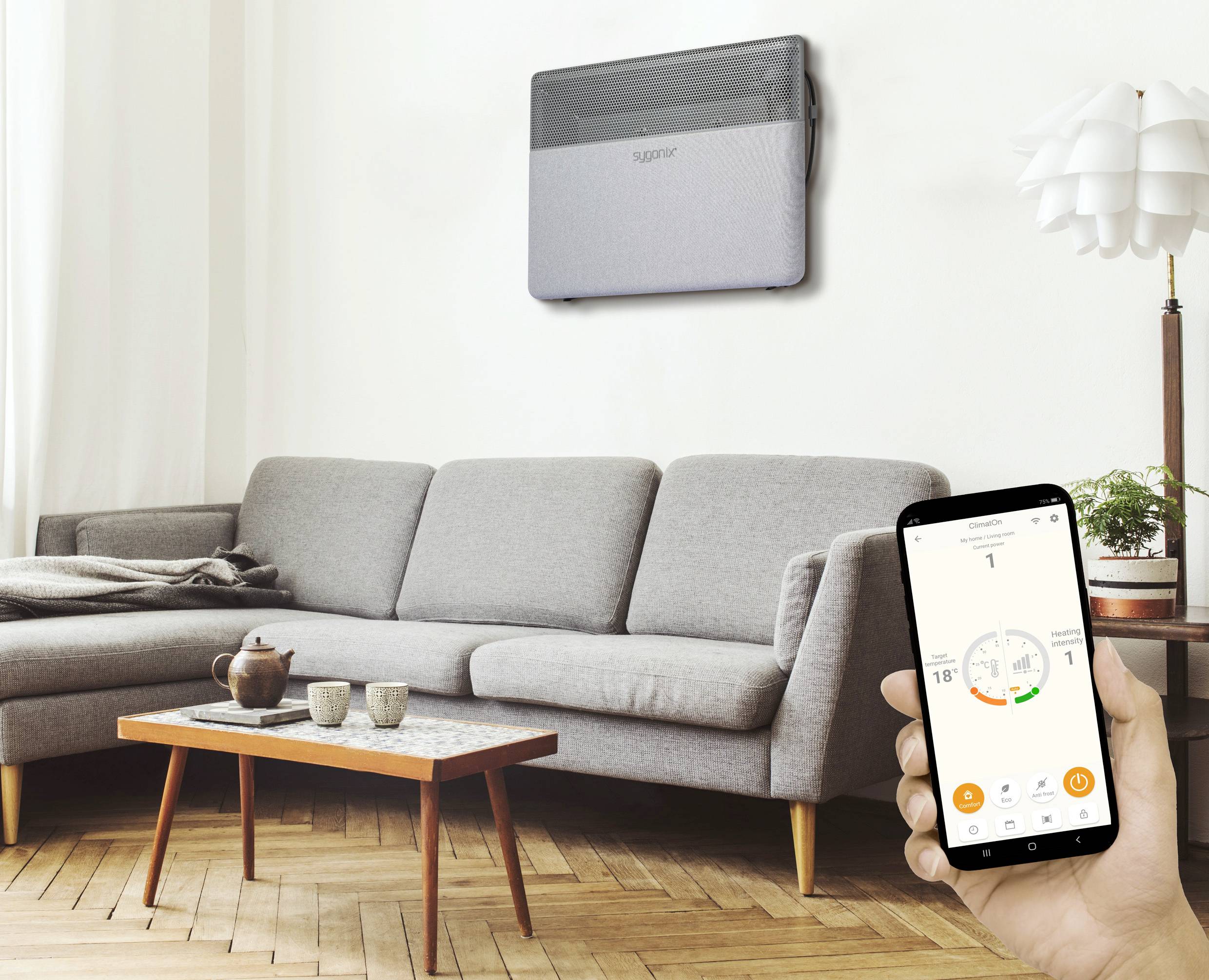 Een woonkamer met een grijze bank, tafel en vloerkleed. Iemand houdt een smartphone vast waarop een klimaatbeheersysteem wordt weergegeven.