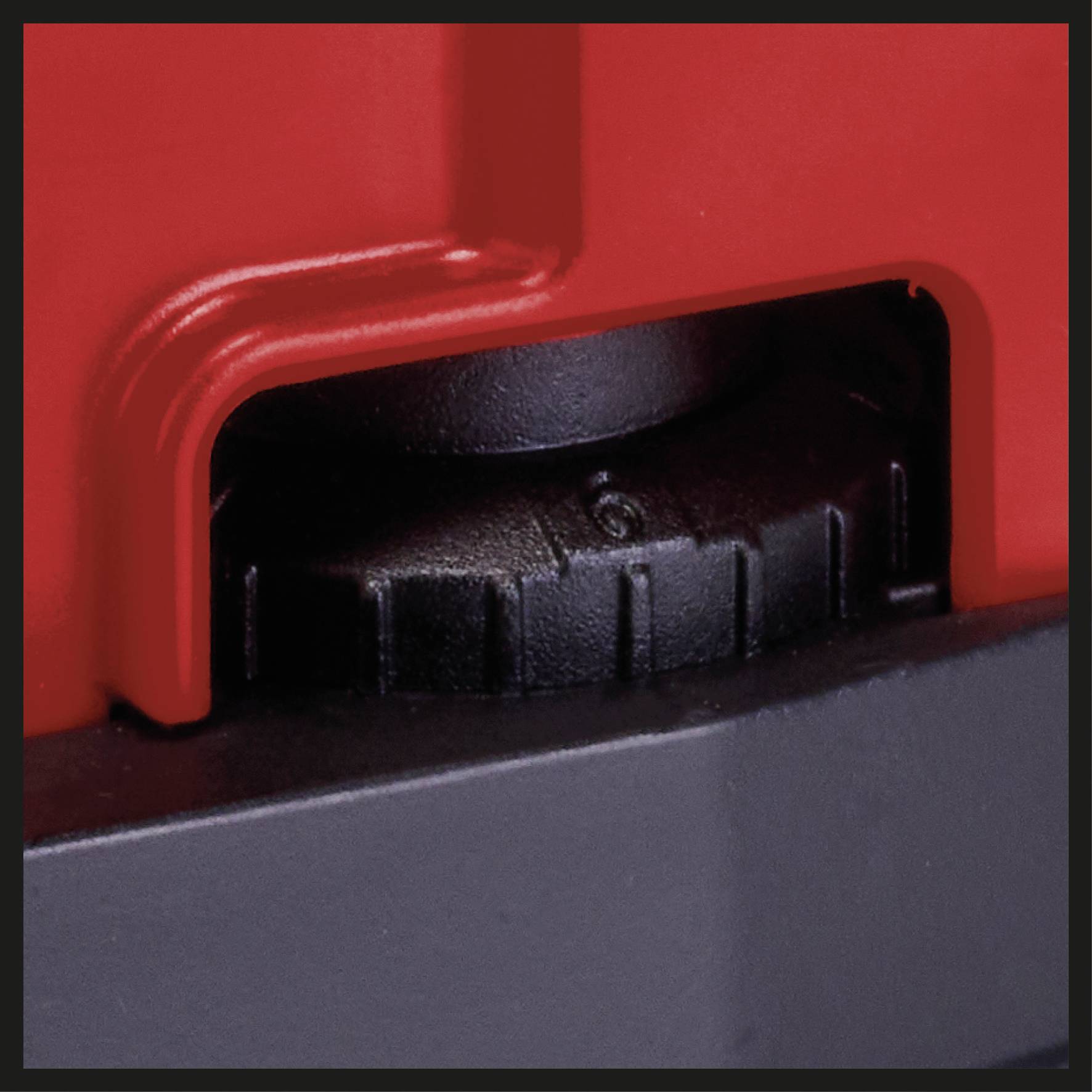 Close-up van een zwart tandwiel, omgeven door rood en zwart behuizingsmateriaal, vermoedelijk onderdeel van een machine of gereedschap.