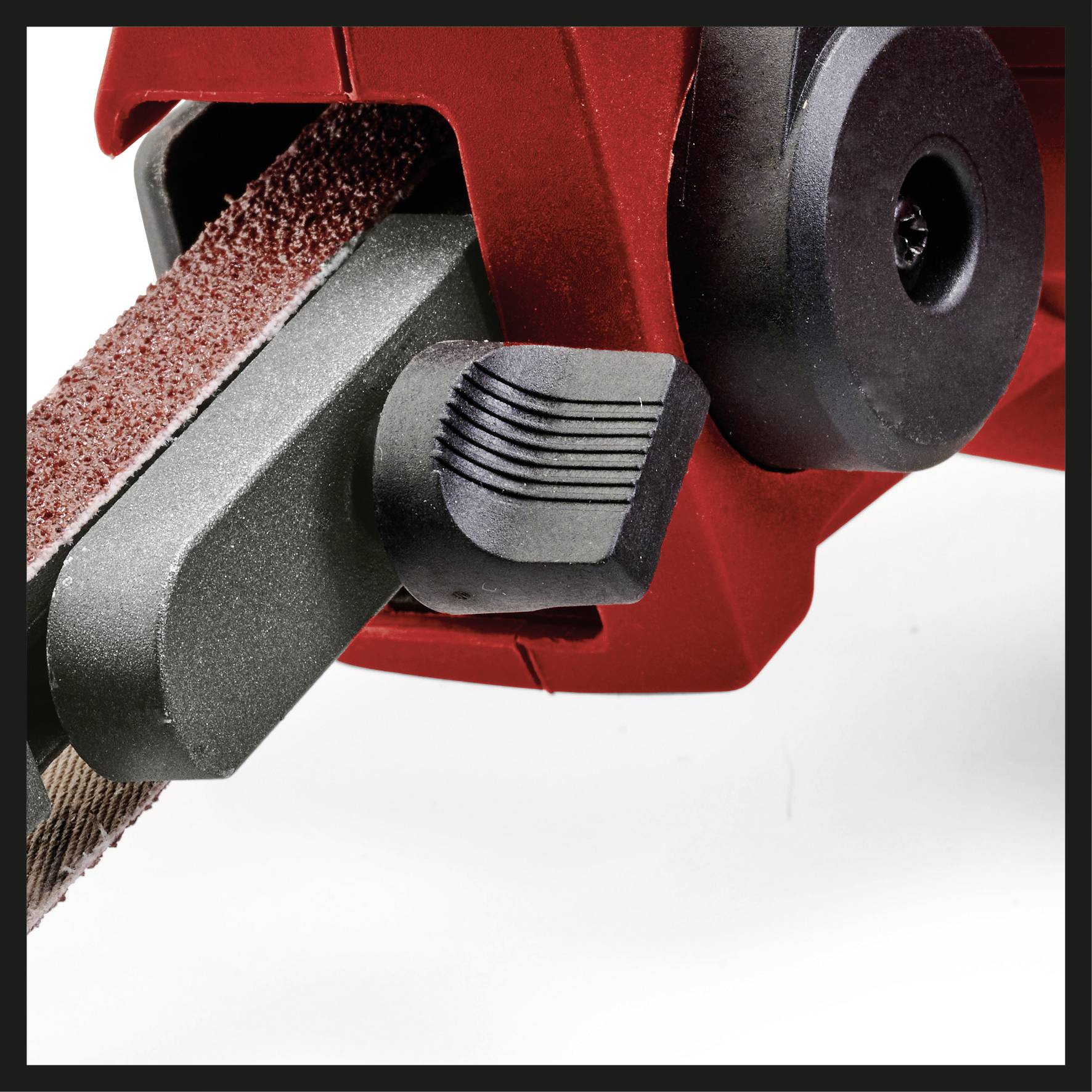 Een bandschuurmachine met een rood behuizing, zwarte handgreep en een grijs schuurband. Het apparaat wordt gebruikt voor oppervlaktebewerking.