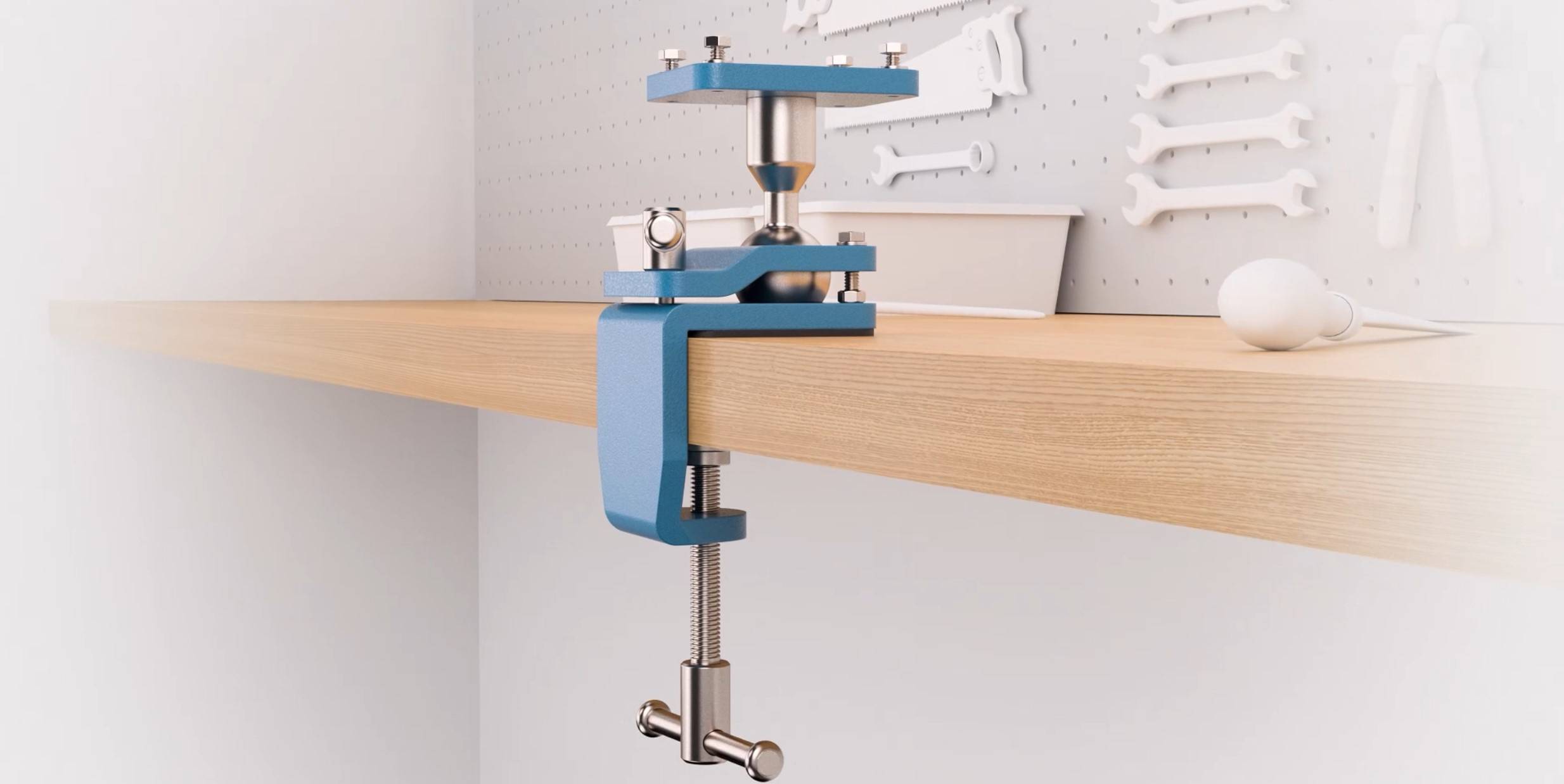 Een kleine blauwe bankschroef is bevestigd aan een houten werkblad. Op de achtergrond hangen moersleutels aan een geperforeerde wand.