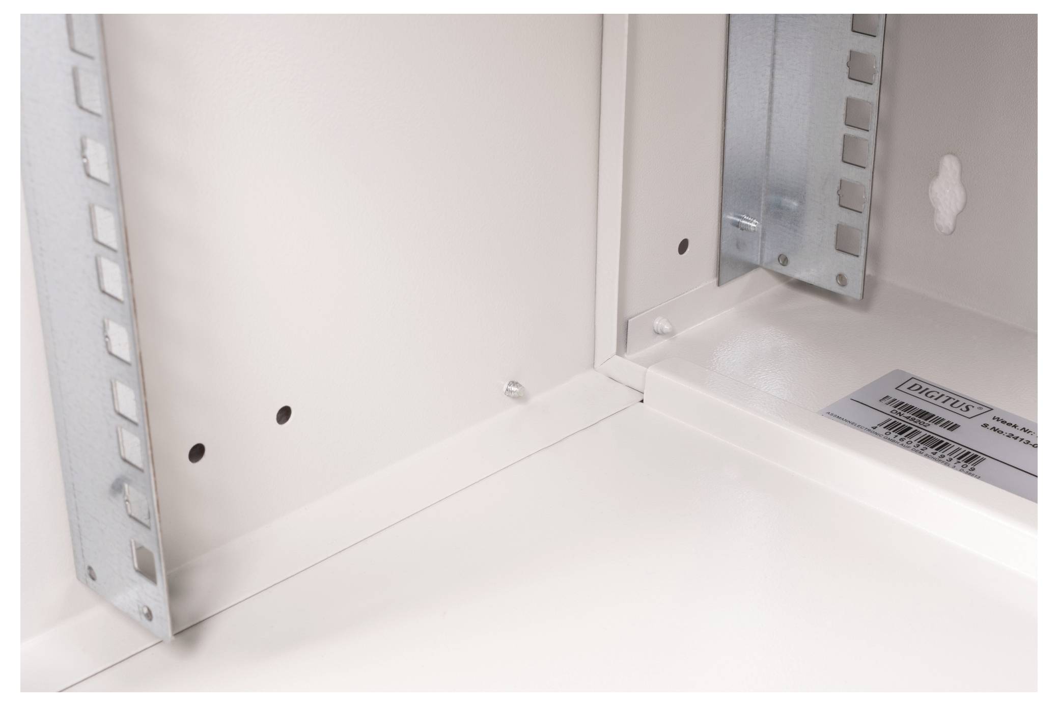 Interieurzicht van een metalen behuizing waarop de hoekconstructie met klinknagels, twee verticale steunbeugels en een fabrikantenlabel te zien zijn.