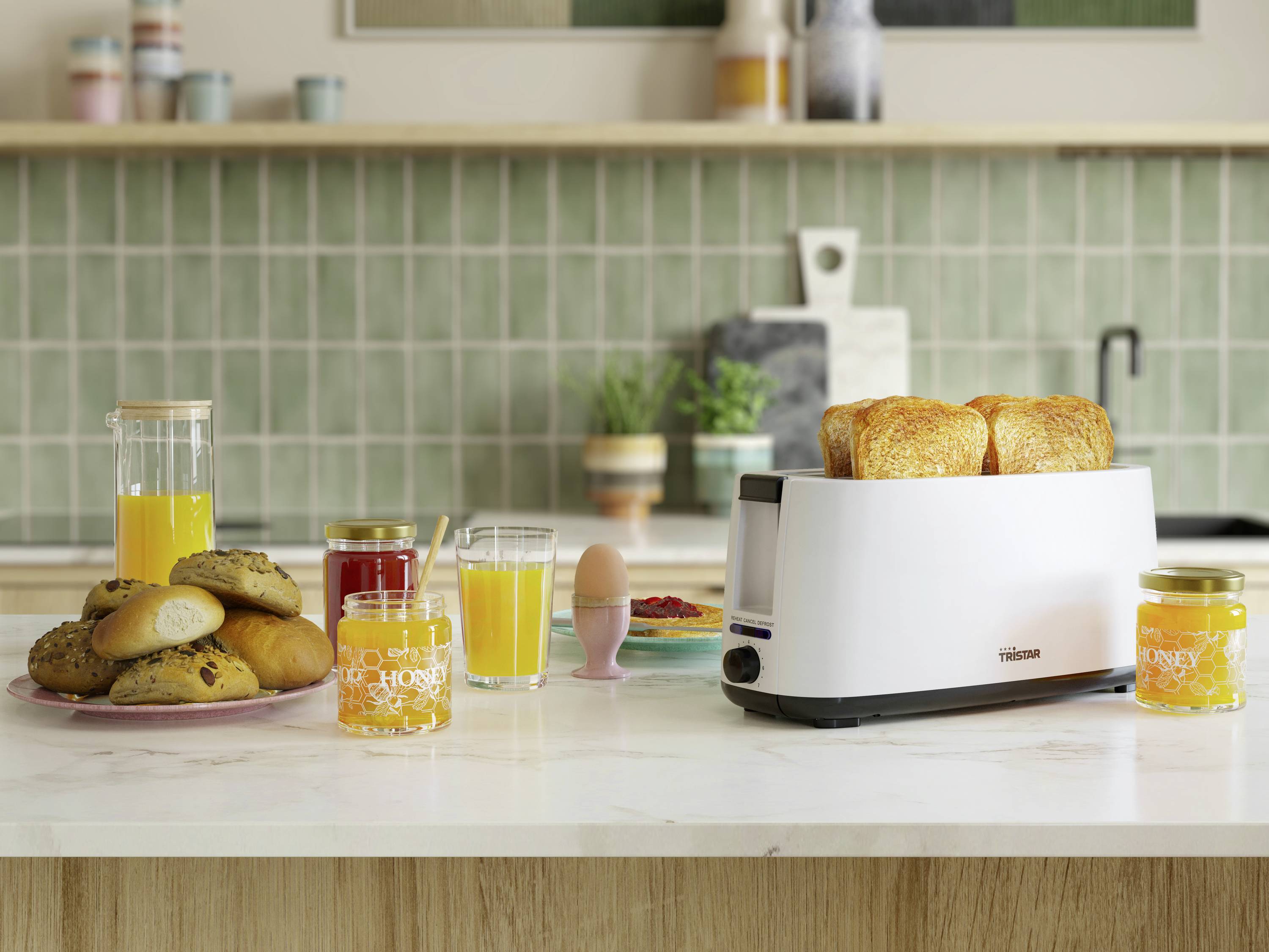 Een gedekte ontbijttafel met een broodrooster en boterhammen, jus d'orange, jam en gebak op een aanrecht voor een betegelde muur.