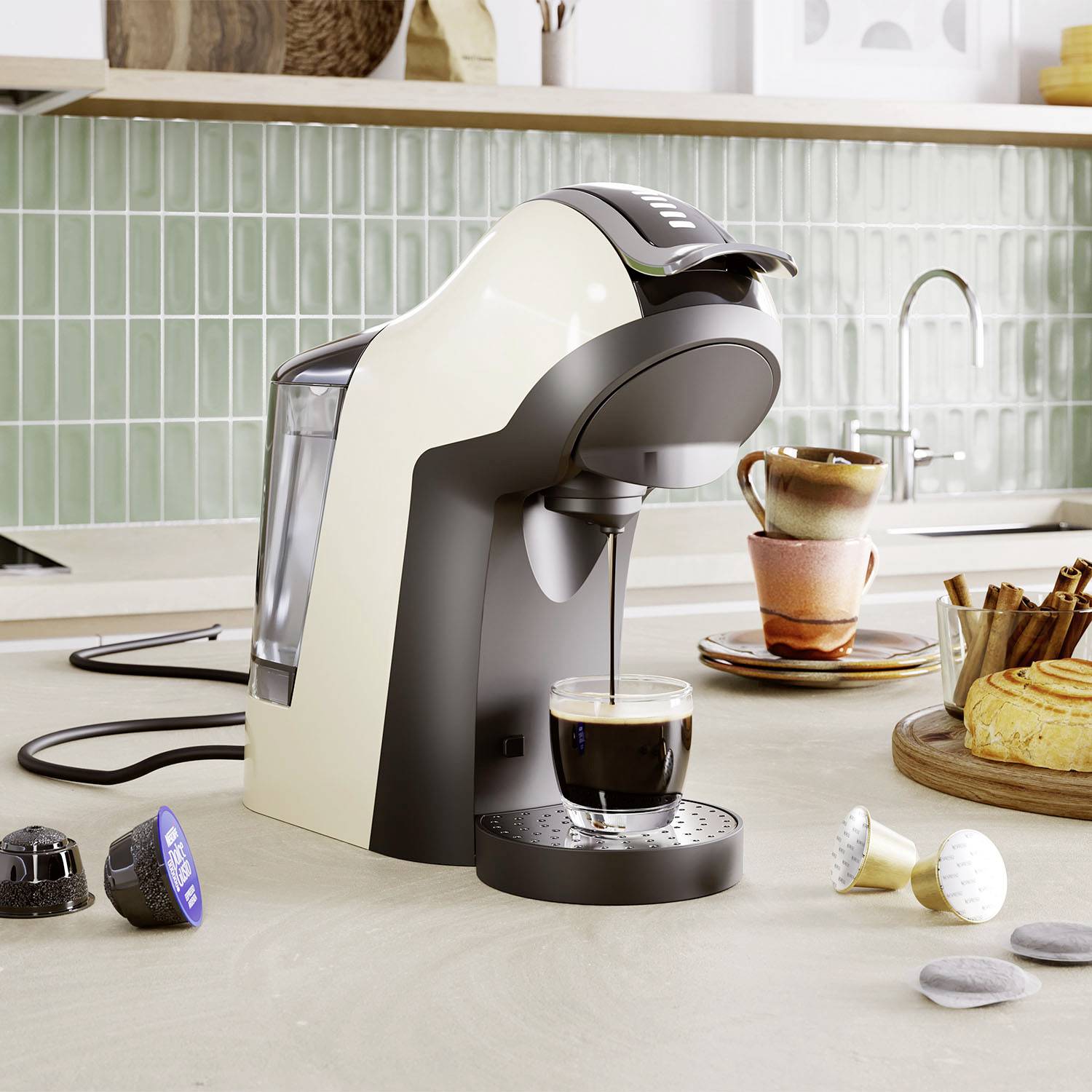 Koffiemachine op een aanrechtblad bereidt een espresso voor. Ernaast staan kopjes, koffiecapsules en een gebakje.