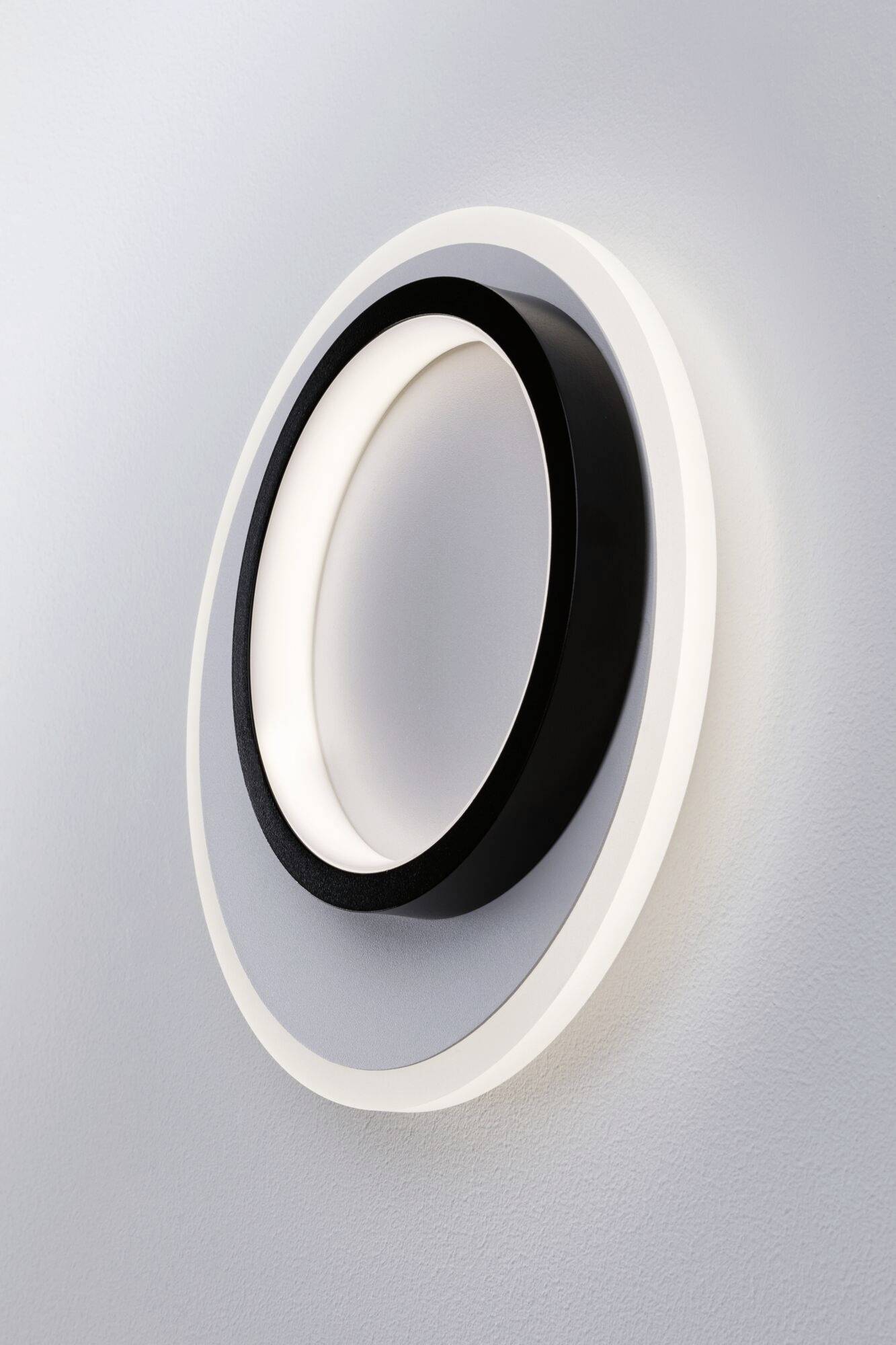 Een moderne, tweekleurige wandlamp met een rond ontwerp in zwart en wit, die indirect licht uitstraalt.