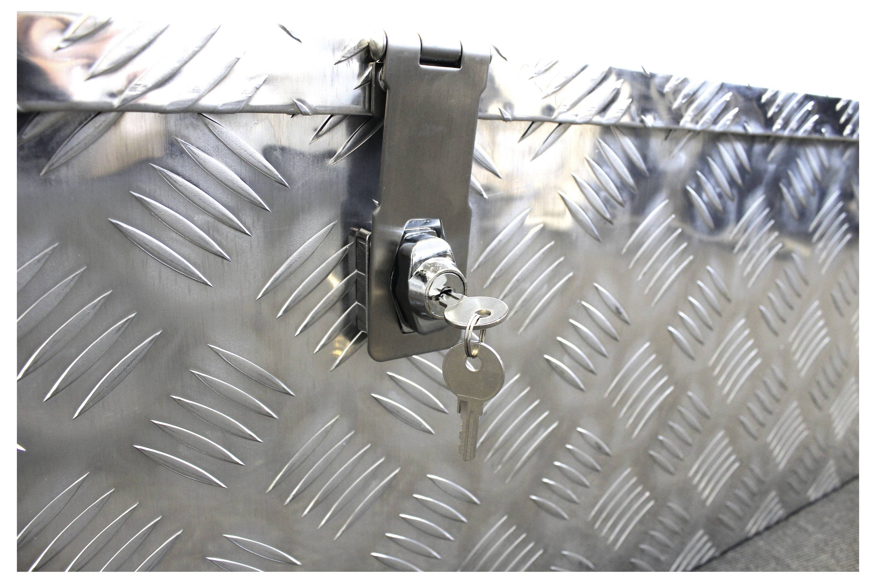 Metalen kist met geribbeld plaatpatroon en een slot waaraan een sleutel hangt.