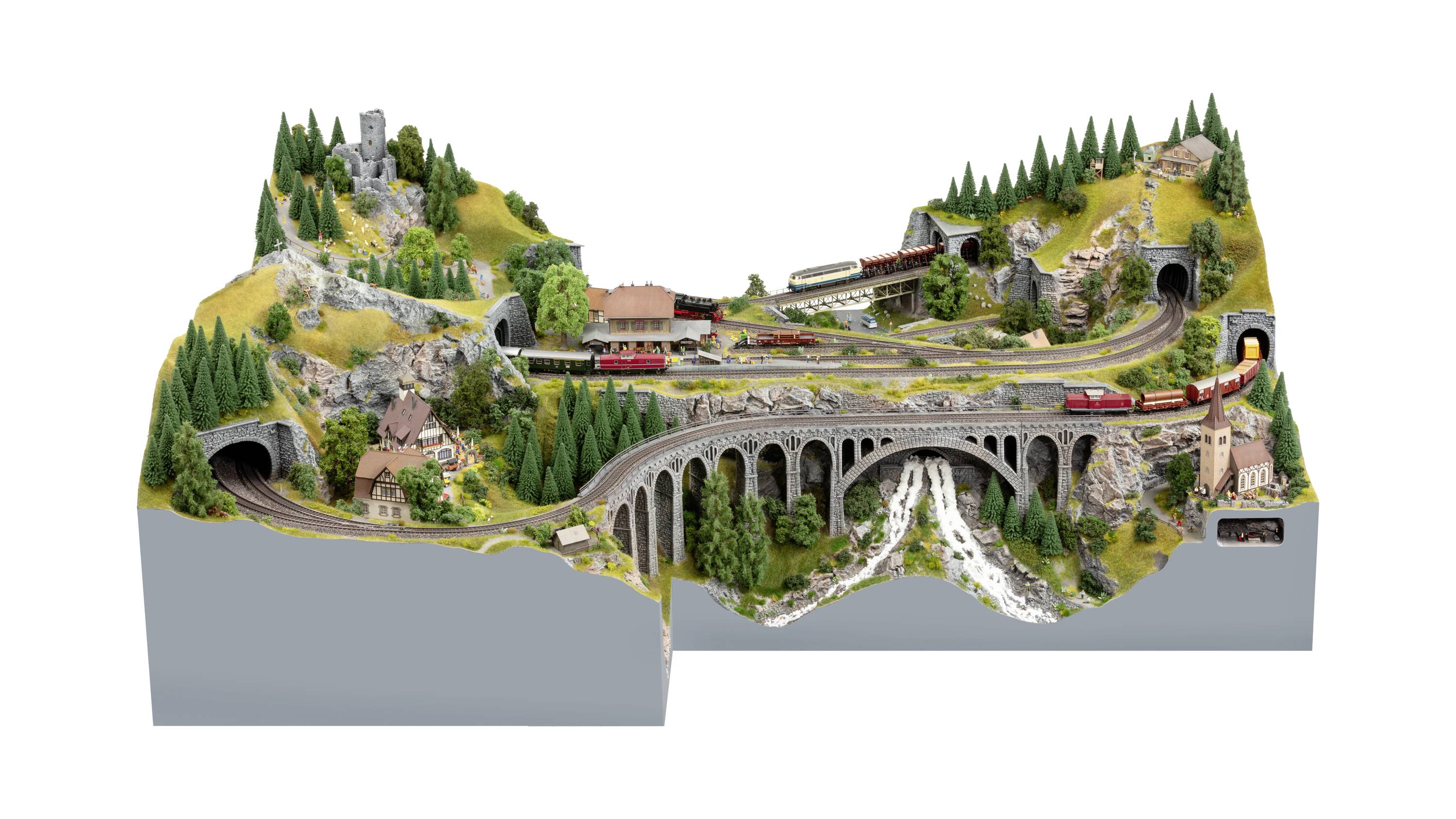 Een gedetailleerd modelsporenlandschap met bruggen, tunnels, bomen en treinen die door een bergachtig landschap rijden.