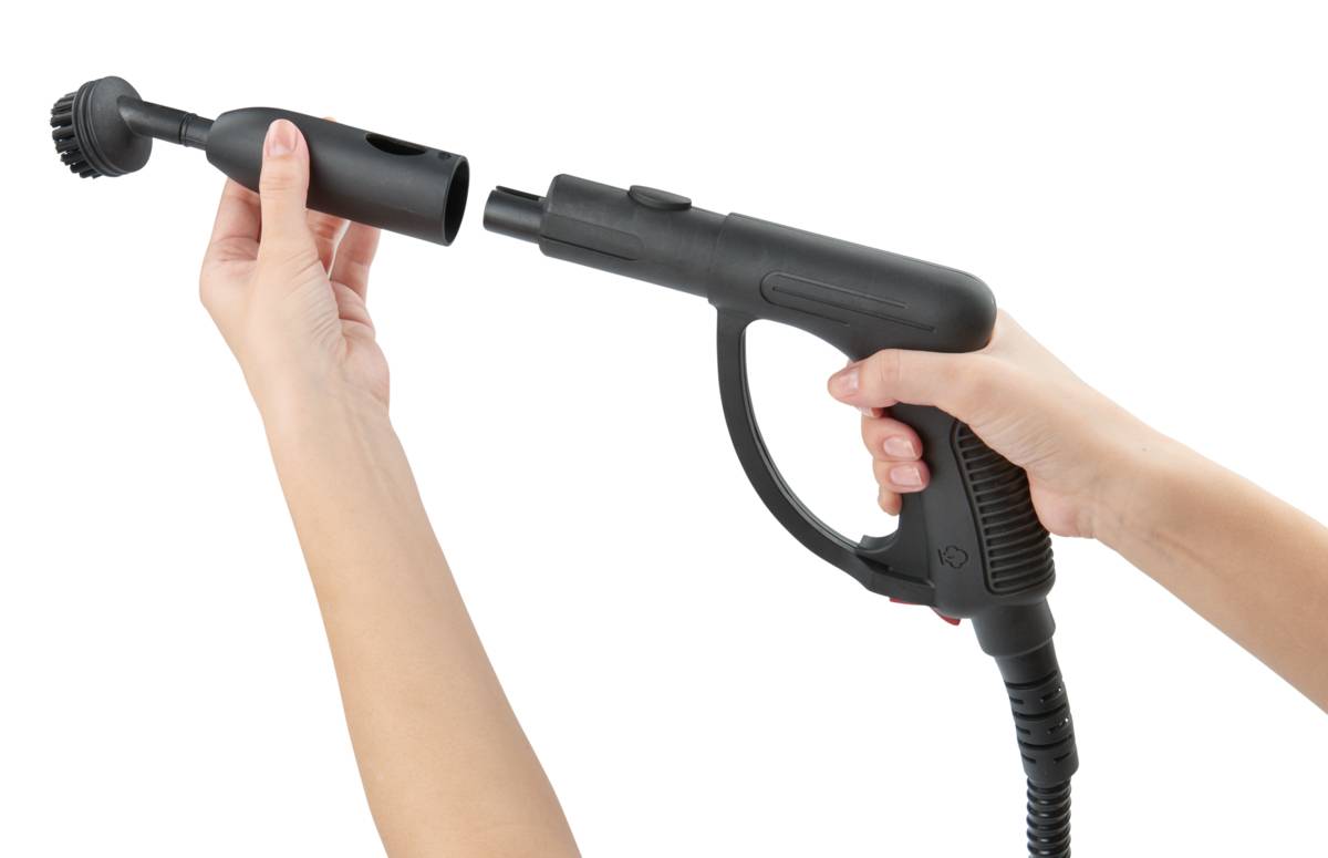 Een persoon houdt een stoomreiniger vast en bevestigt een borstelmond, klaar om schoon te maken.