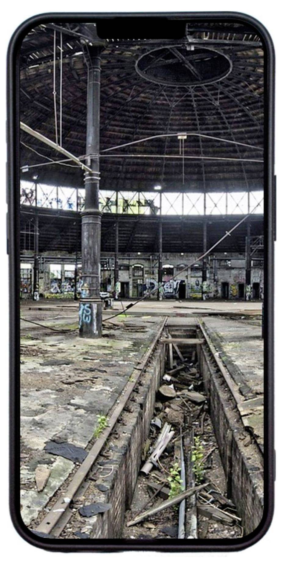 Een oude, vervallen industrieel gebouw met graffiti op de muren, bekeken door het scherm van een smartphone.