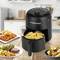 Friteuse op tafel in keuken, gevuld met friet. Omringd door borden met steak, friet, chicken wings en dip.