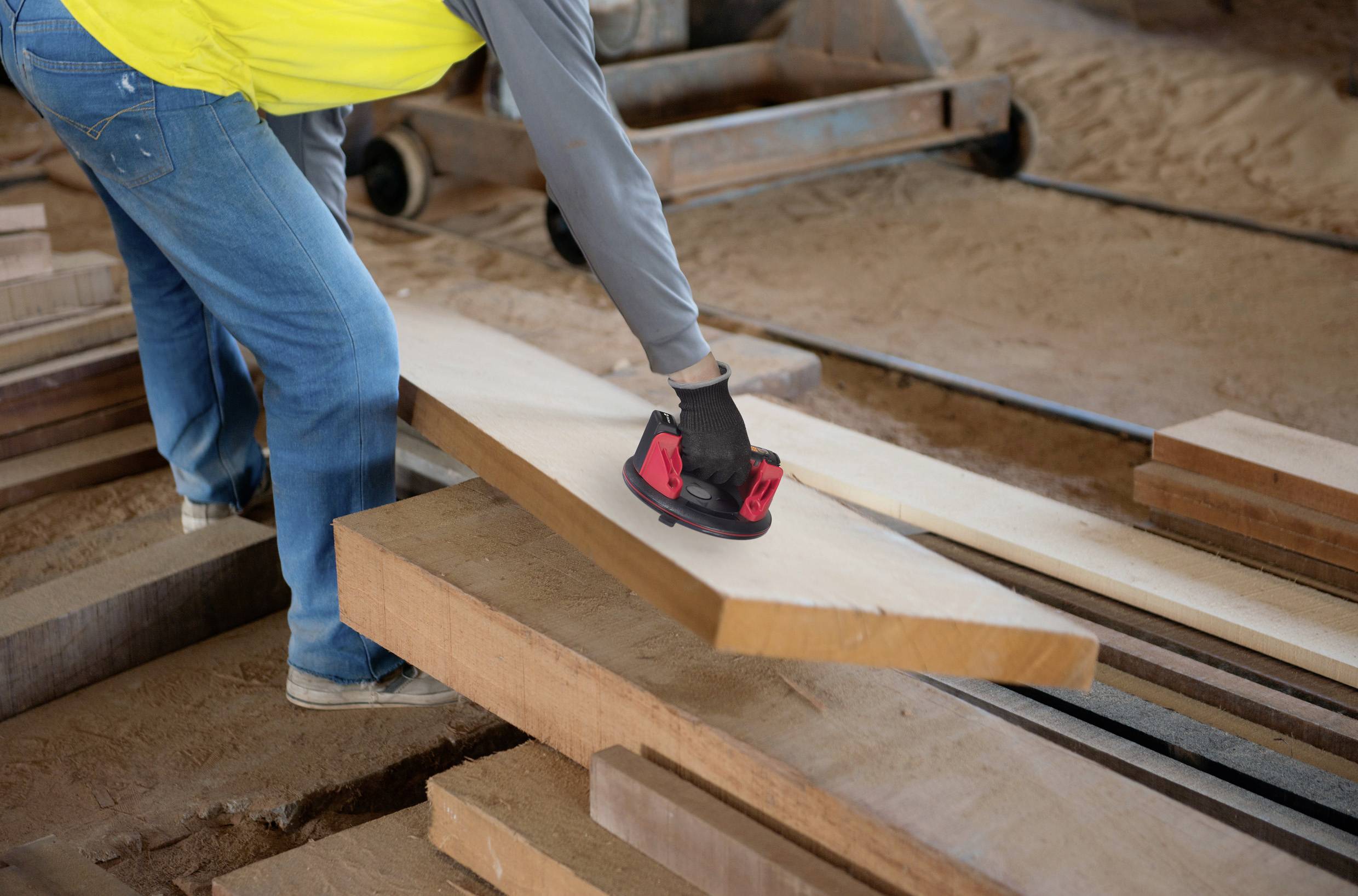 Een persoon schuurt houten planken met een handschuurmachine in een werkplaats. Het betreft een ambachtelijke activiteit.