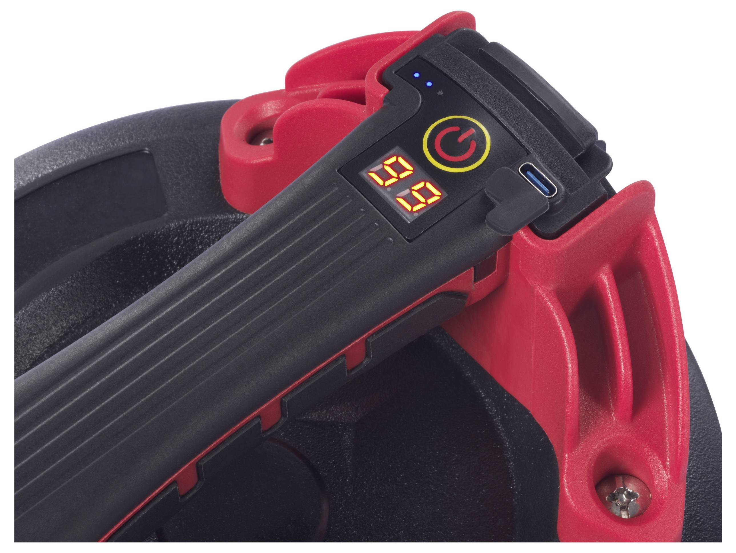 Close-up van een zwart en rood apparaat met een digitaal scherm en laadaansluiting. Display toont '99', naast de aan/uit-knop die oplicht.