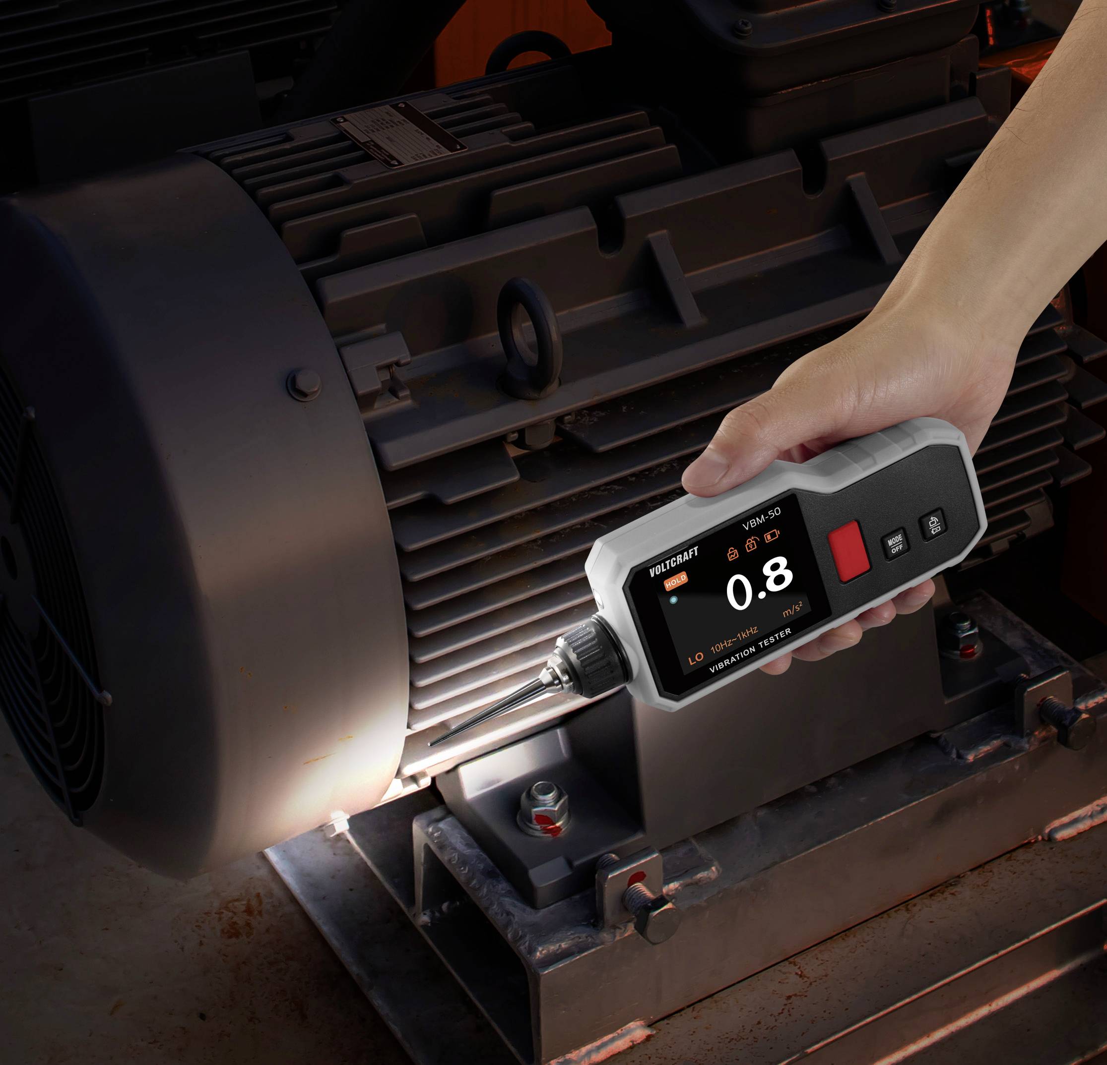 Een hand bedient een digitale momentsleutel op een industriële motor, waarbij op het scherm een momentwaarde van 0,8 wordt weergegeven.