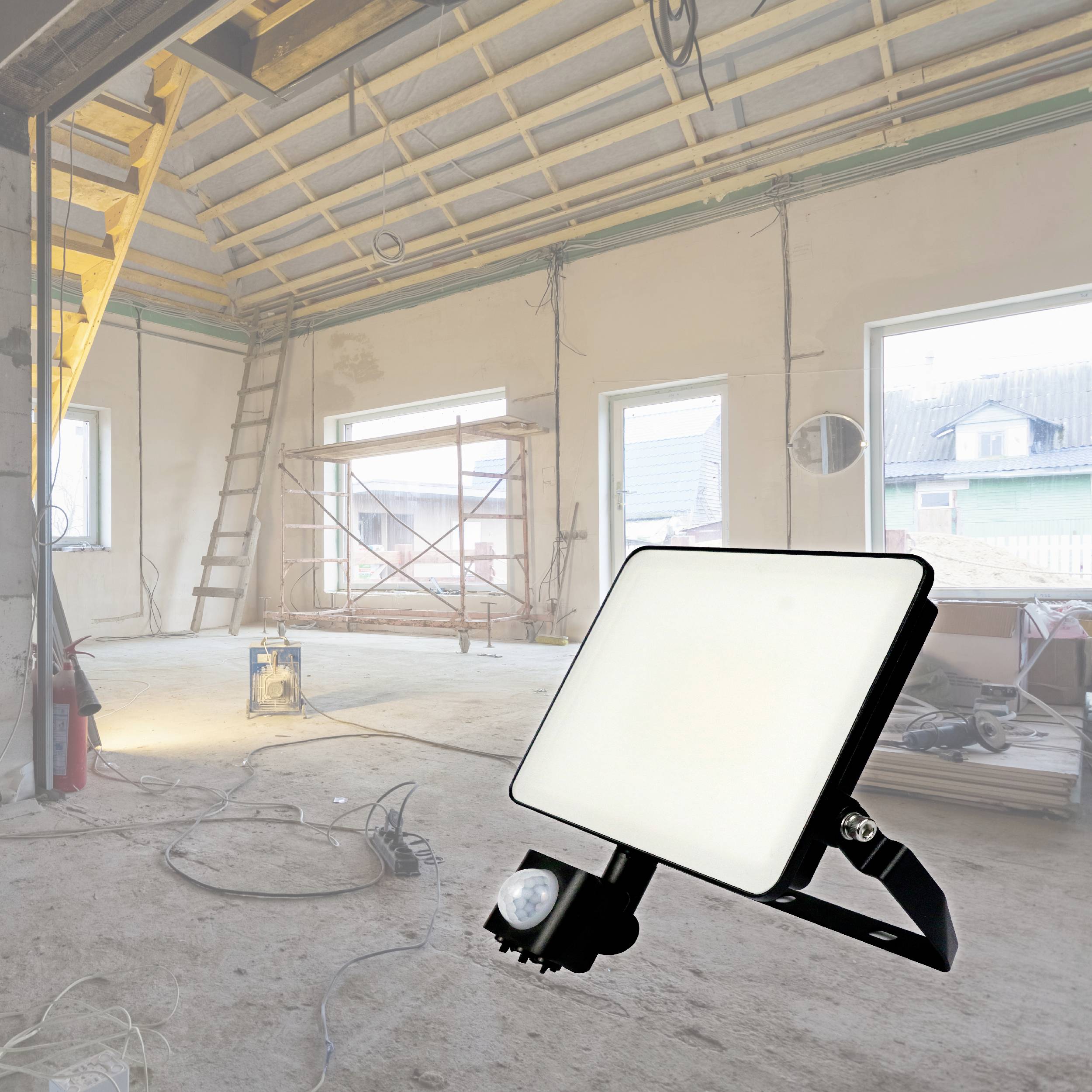 Een ongerenoveerde woning met zichtbare plafondbalken, ladder en steiger. Op de voorgrond een bouwlamp die de ruimte verlicht.