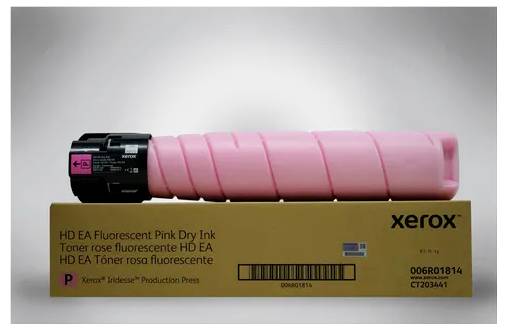 Een roze Xerox-tonercartridge ligt op een verpakking. De kartonnen doos vertoont opdrukken zoals 'HD EA Fluorescent Pink Dry Ink'.